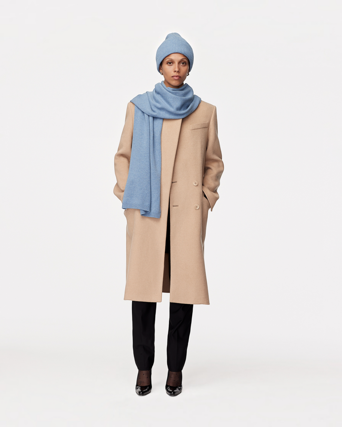 Weldun cornflower blue recycled cashmere scarf worn by a model in a beige wool coat and matching beanie