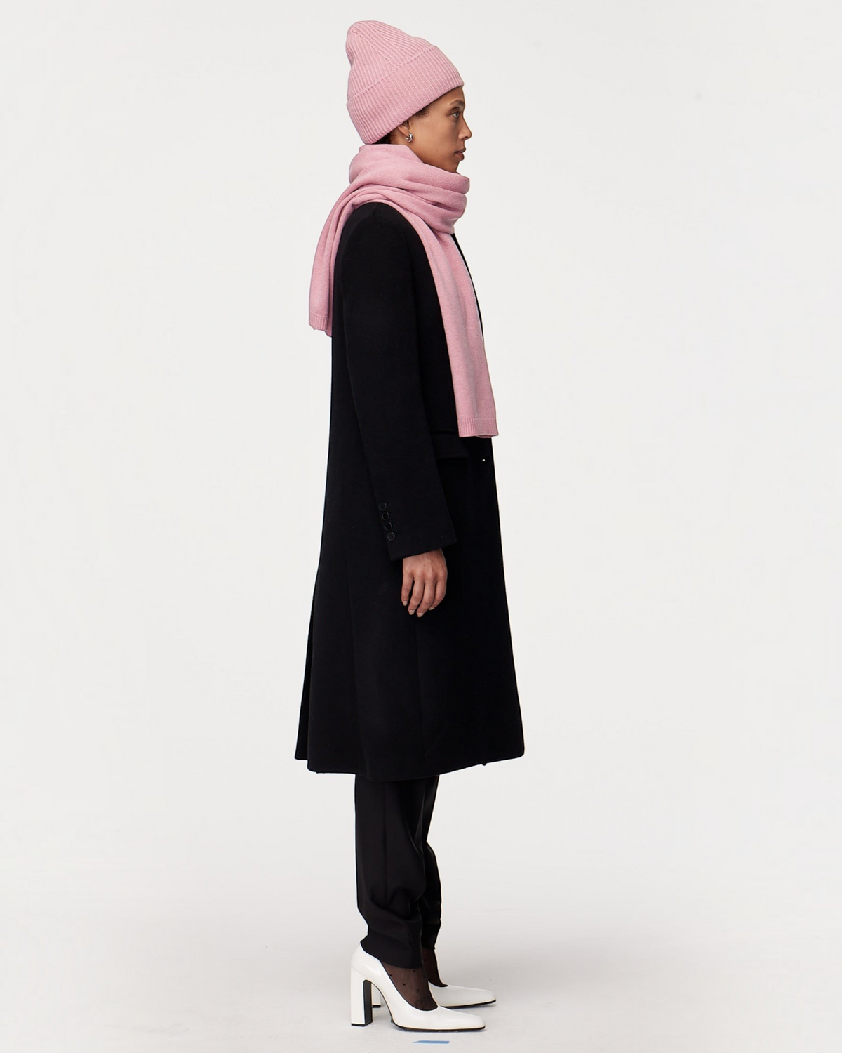 Weldun orchid recycled cashmere scarf worn by a model in a black coat and matching pink beanie, side profile view.