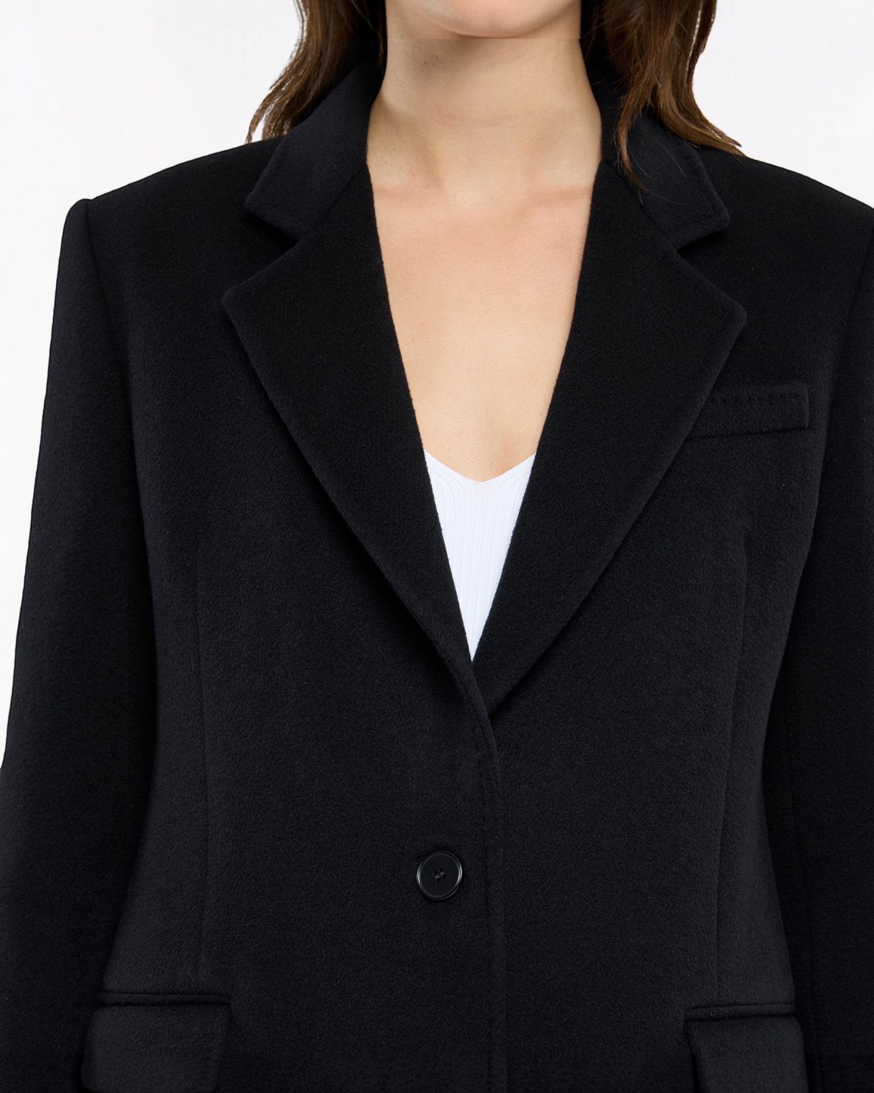 Weldun black tailored cashmere overcoat with notched lapels and single-button closure worn over a white top