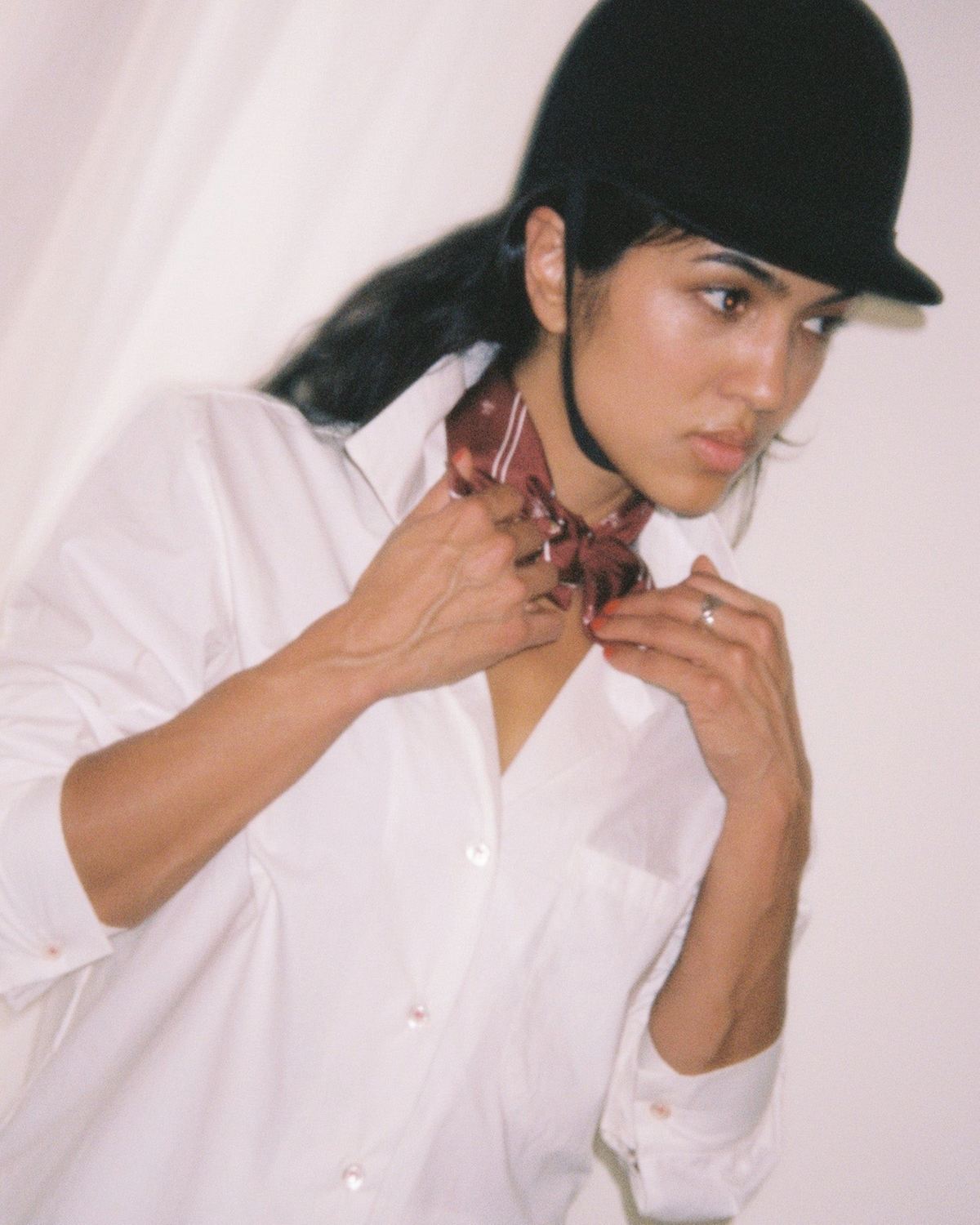 Weldun Petit Circus 55 silk twill bandana in burgundy worn around the neck by a woman in a white shirt and riding hat