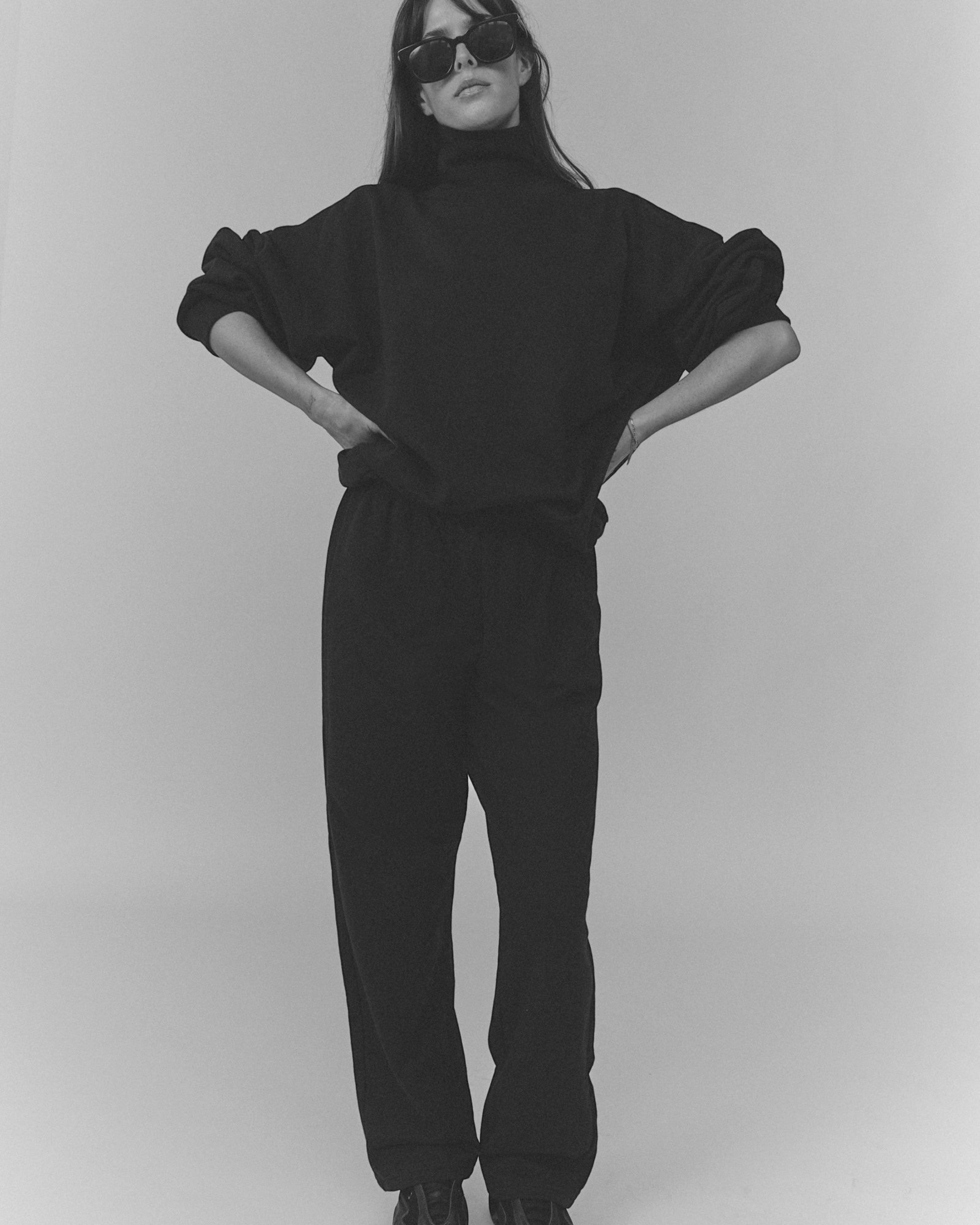 Model wearing Weldun navy organic cotton high neck sweatshirt and matching sweatpants with sunglasses