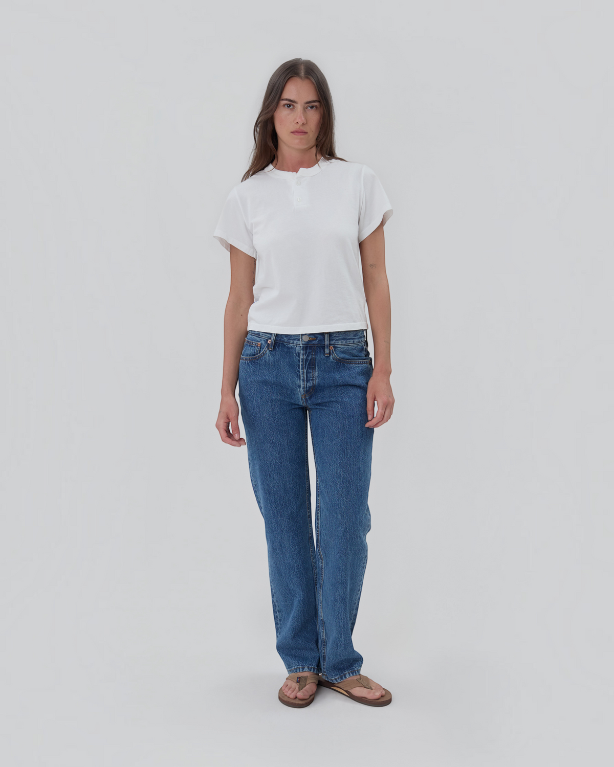 Weldun model wearing a white short sleeve cotton Henley shirt with a two-button placket and blue side tab.