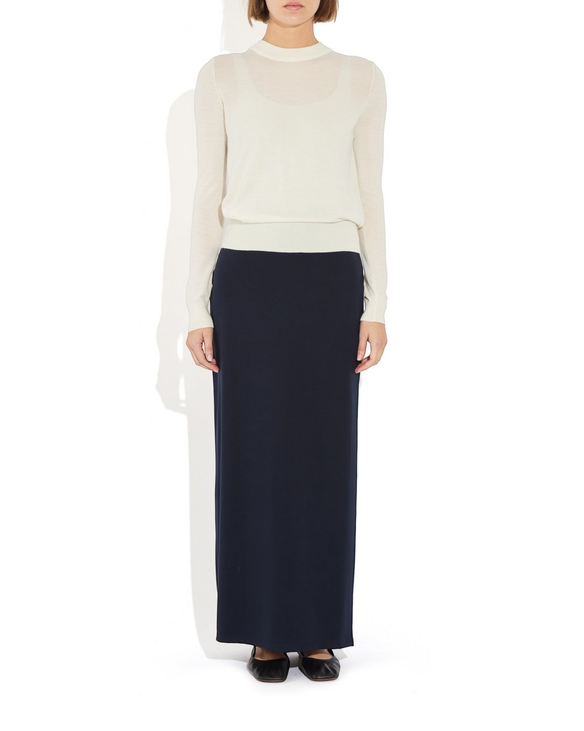 Weldun Ashley skirt in a dark navy fluid column silhouette with a side slit, worn with a cream long-sleeve top.