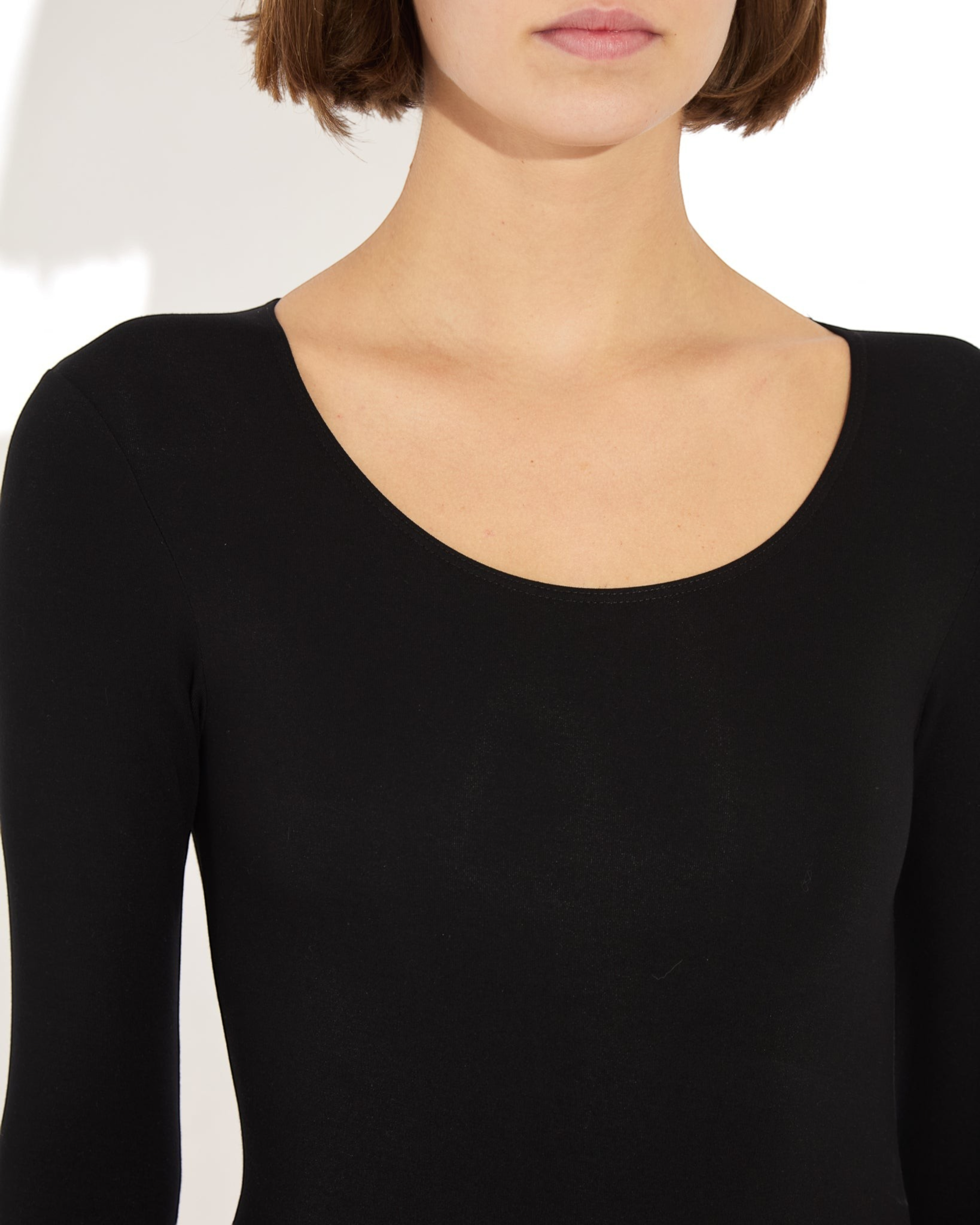 Weldun Donna long-sleeve black scoop neck bodysuit in soft stretch-knit fabric worn by a model