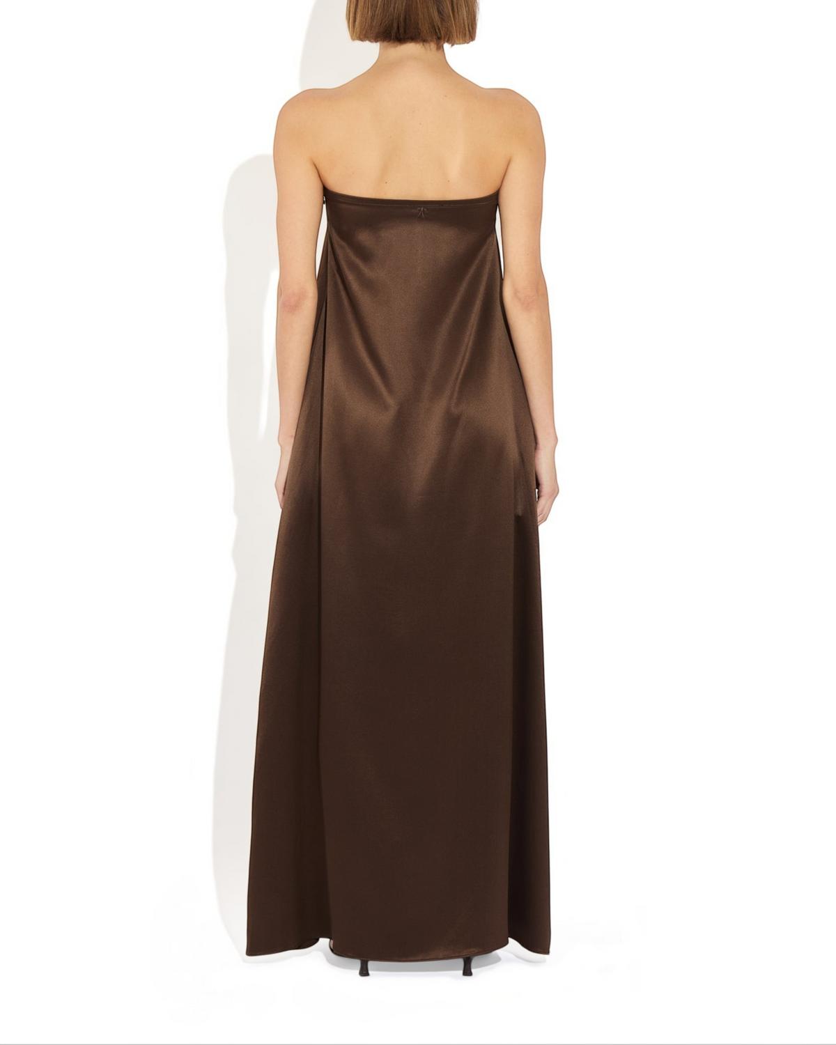 Back view of a model wearing a Weldun Edith Gown, a strapless brown silk satin maxi dress with a trapeze silhouette.