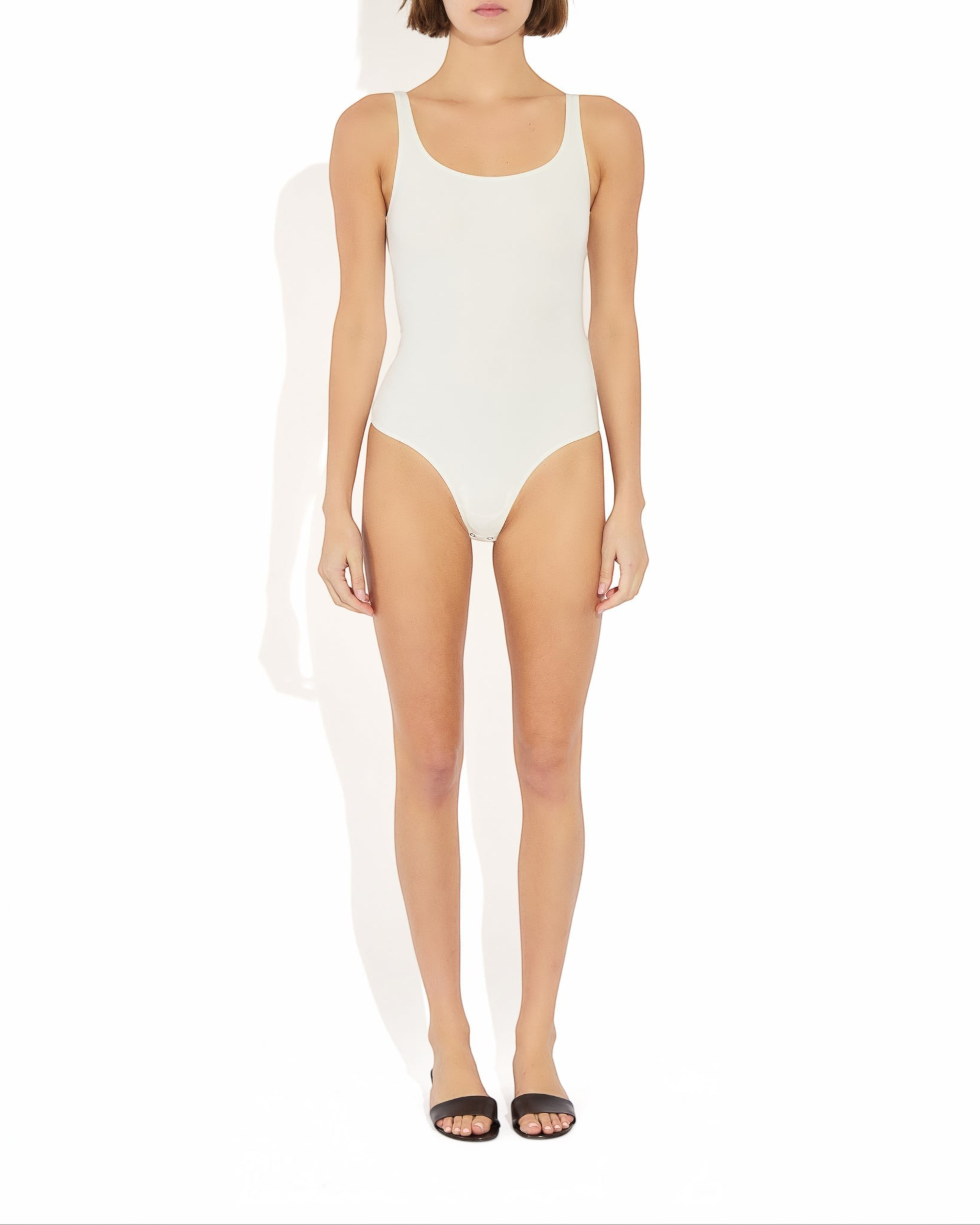 Model wearing a Weldun white Lisa tank bodysuit with a scoop neckline and cheeky cut in breathable stretch fabric