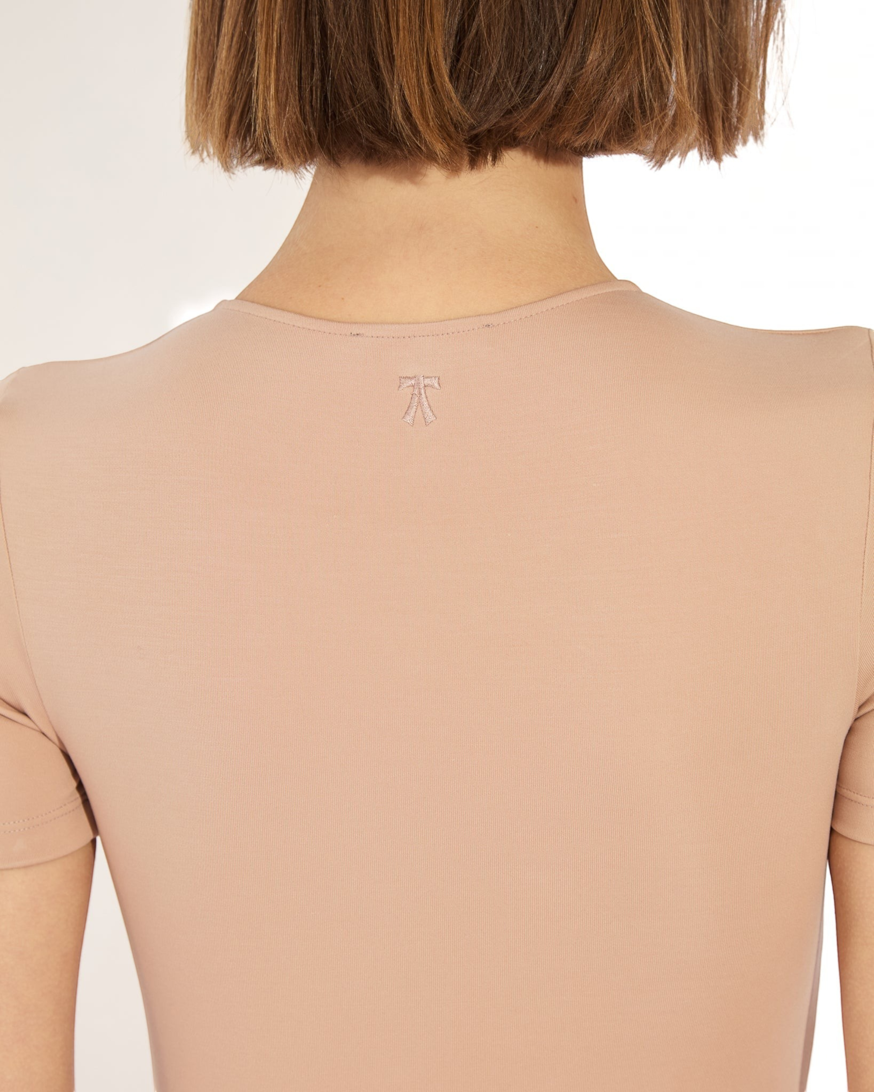 Weldun Penny Bodysuit in beige MicroTencel fabric featuring a short-sleeve design and a small embroidered bow detail.