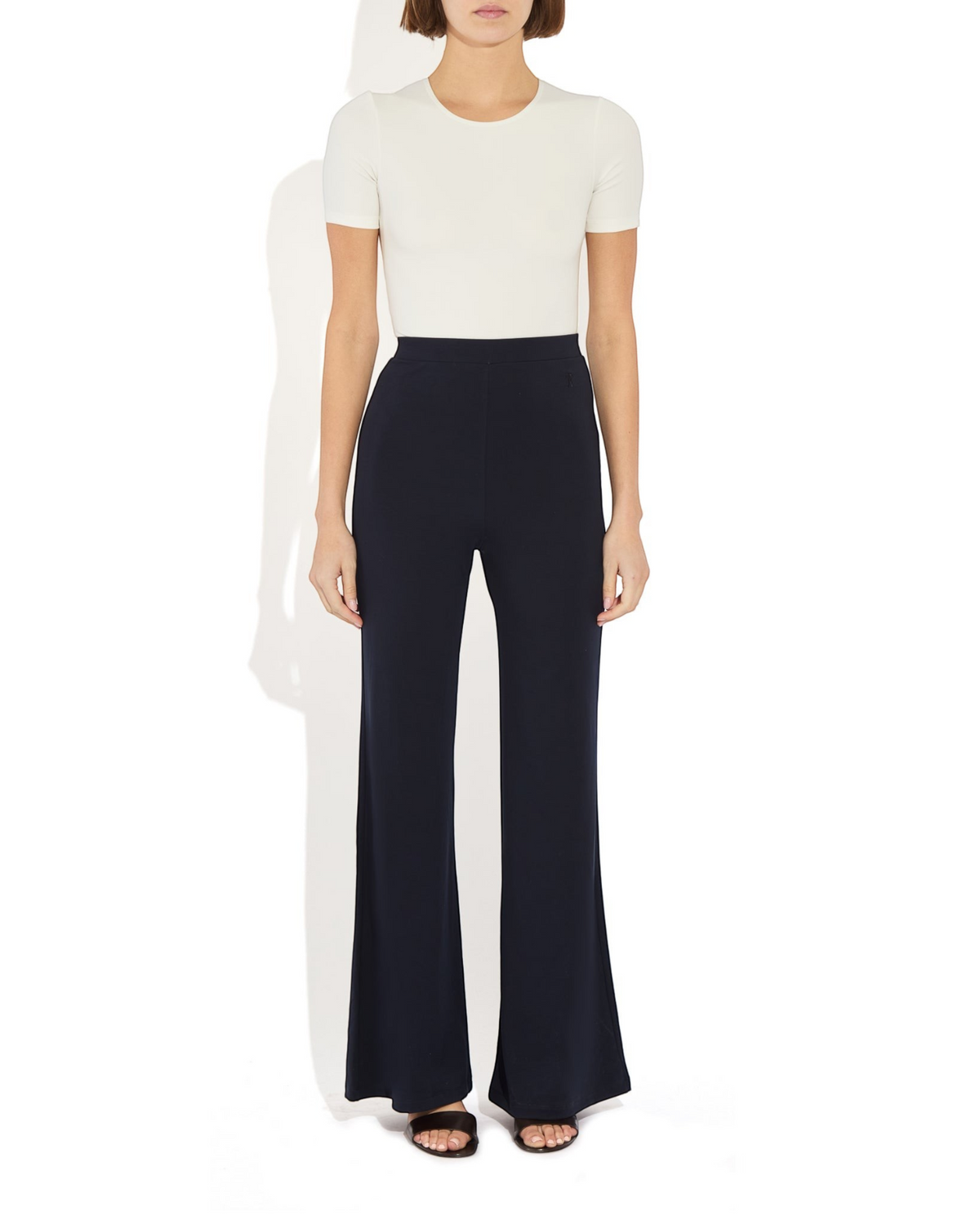 Weldun Penny Bodysuit in cream with a ballerina neckline and short sleeves worn with black wide-leg trousers
