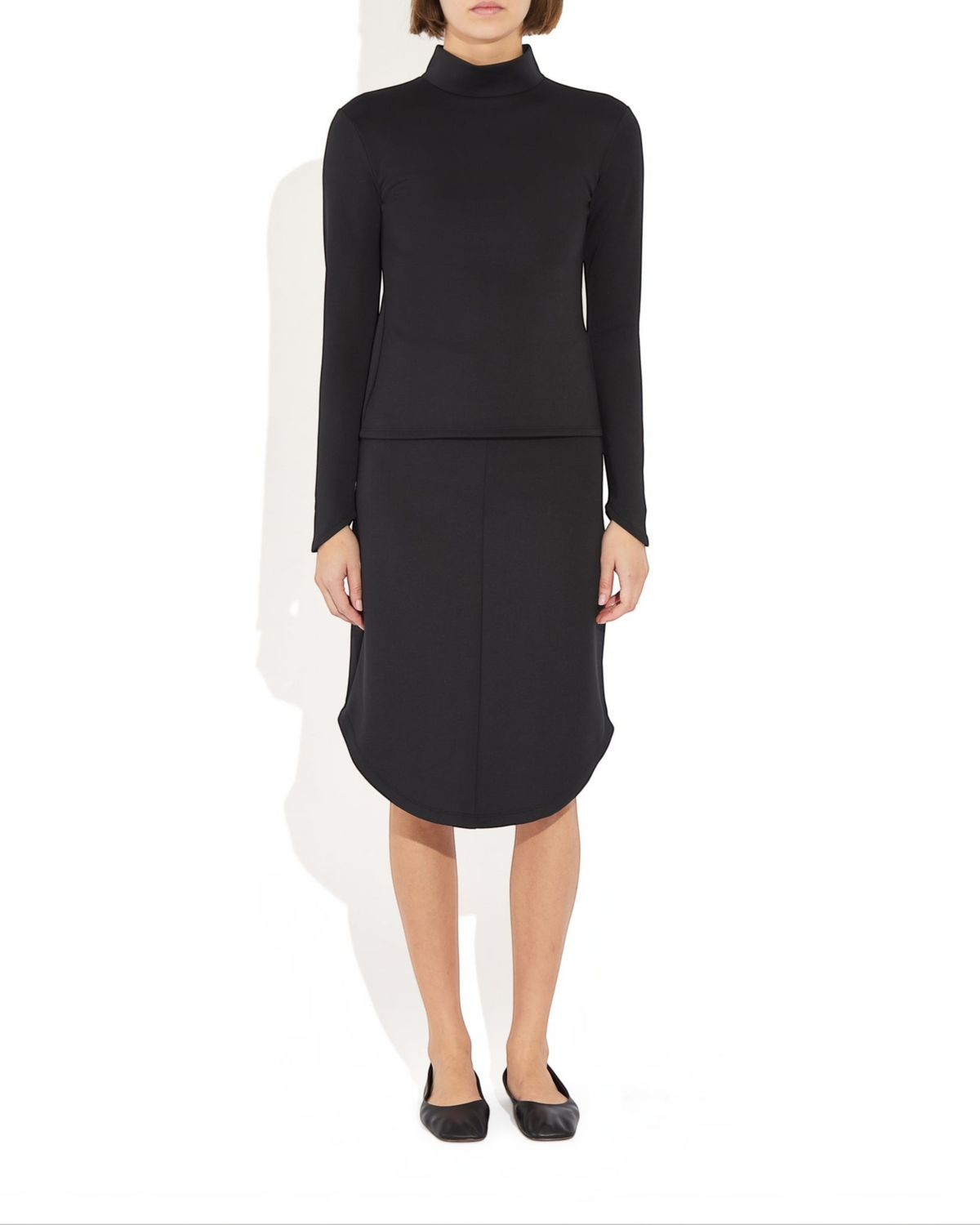 Weldun Rose Skirt in black stretch recycled-poly blend with a sculptural rounded hem and pencil silhouette