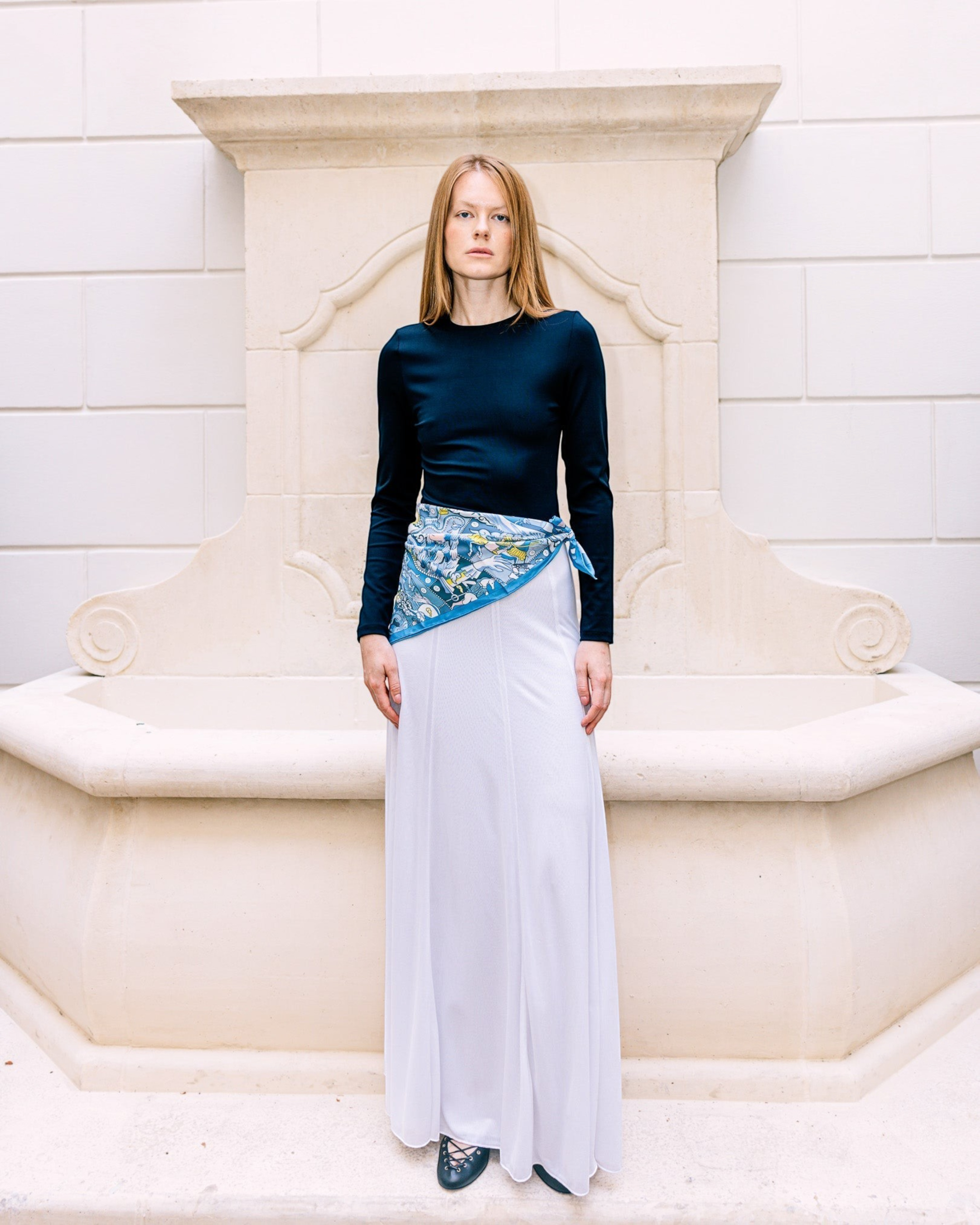 Weldun Semi-Sheer Olivia maxi skirt in white lyocell with elastic waistband, worn by a model in a stone courtyard.