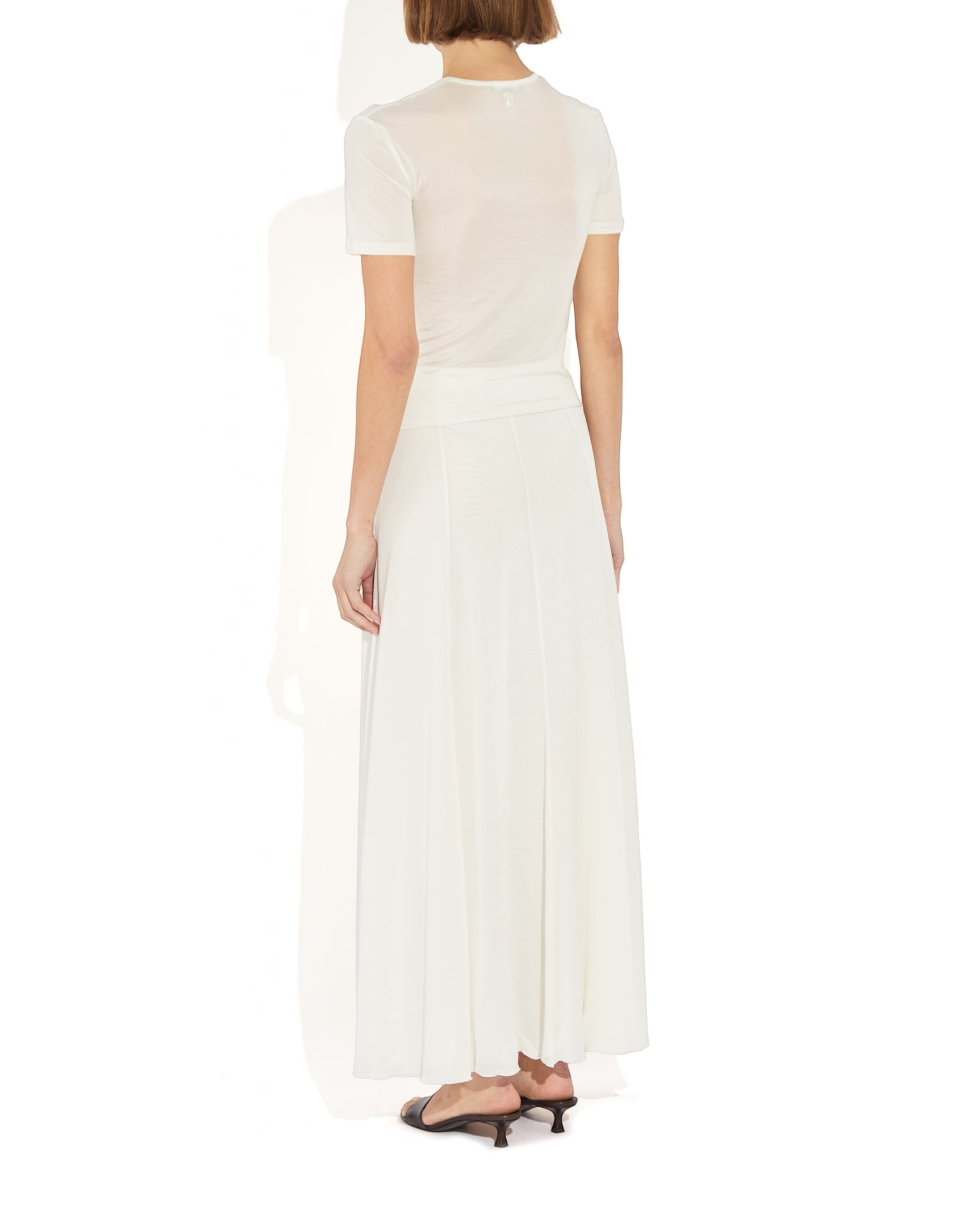 Back view of a model wearing the Weldun Semi-Sheer Olivia maxi skirt in white, featuring a fluid, layered design.