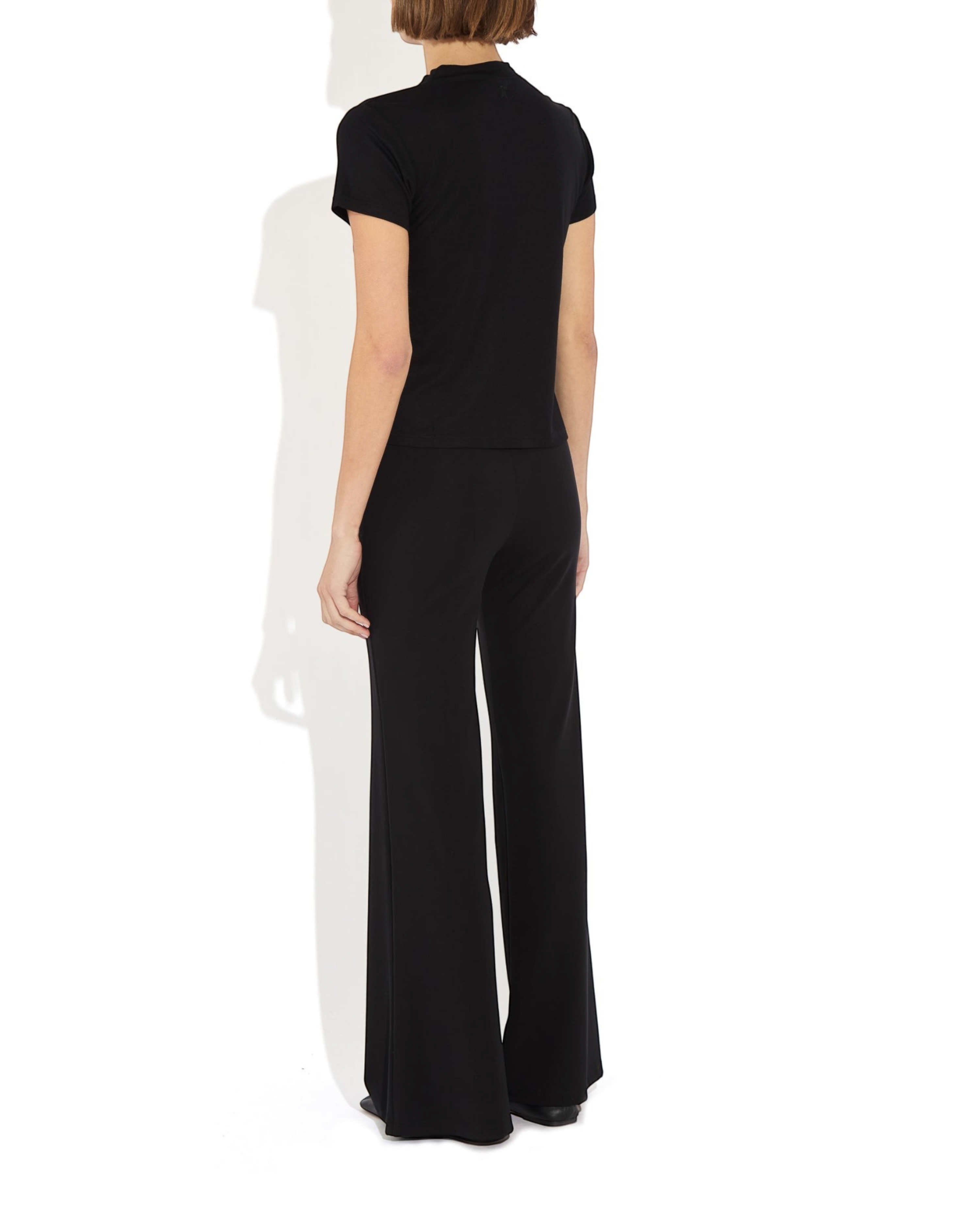 Model wearing Weldun Tessa Long Pant in black with a high elasticated waist and fluid flare leg design.