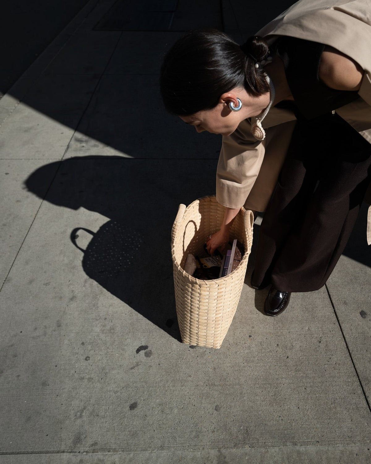 Weldun Big Shopper oversized rattan basket bag held by a woman on a city sidewalk in natural light