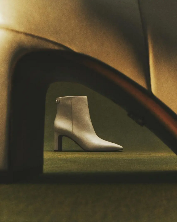 Silver ankle boot on a textured surface with a warm light