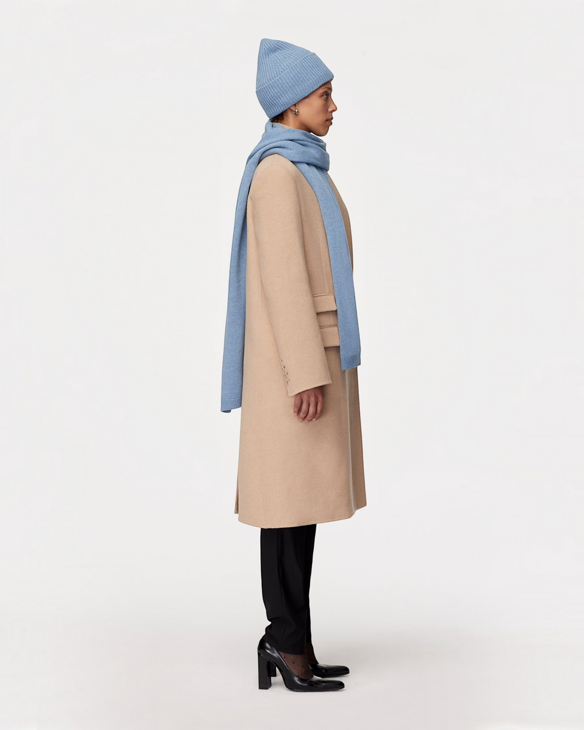 Weldun cornflower blue recycled cashmere scarf worn with a matching beanie and beige coat on a model