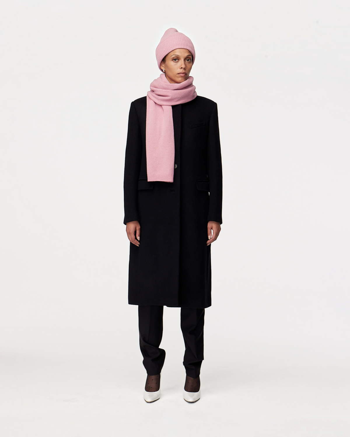 Model wearing a Weldun orchid recycled cashmere scarf and matching beanie with a black coat against a white background.