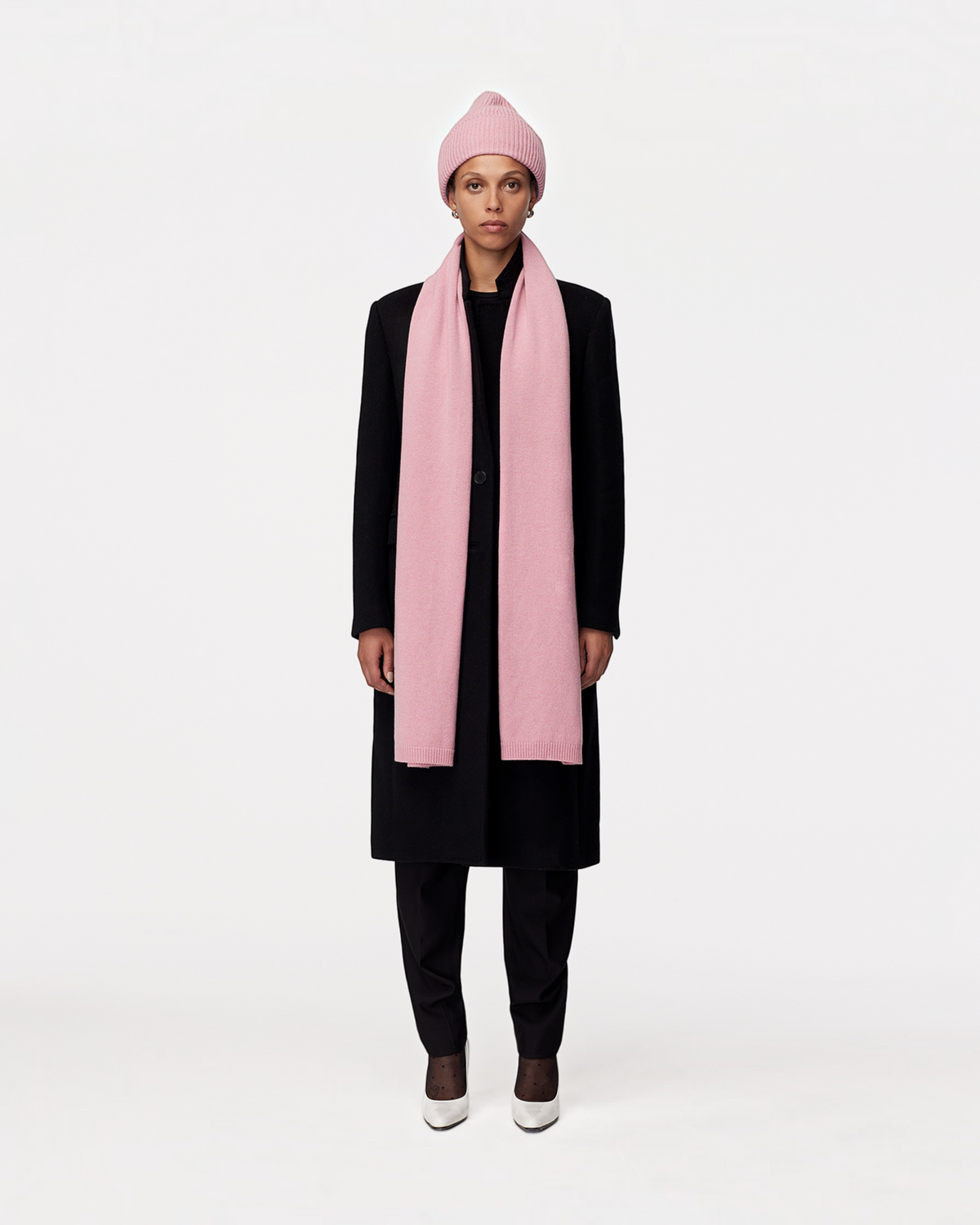 Model wearing a Weldun orchid recycled cashmere scarf and matching beanie with a black coat against a white background