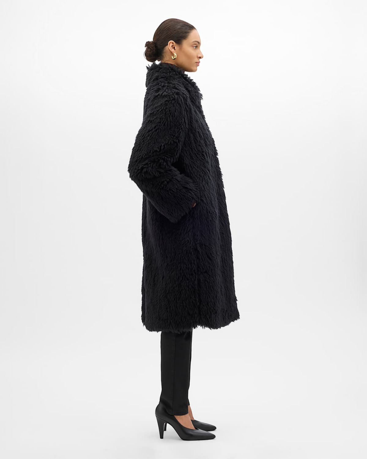 Weldun black faux fur Balmacaan coat with an oversized fit, point collar, and frog closures, side profile view.