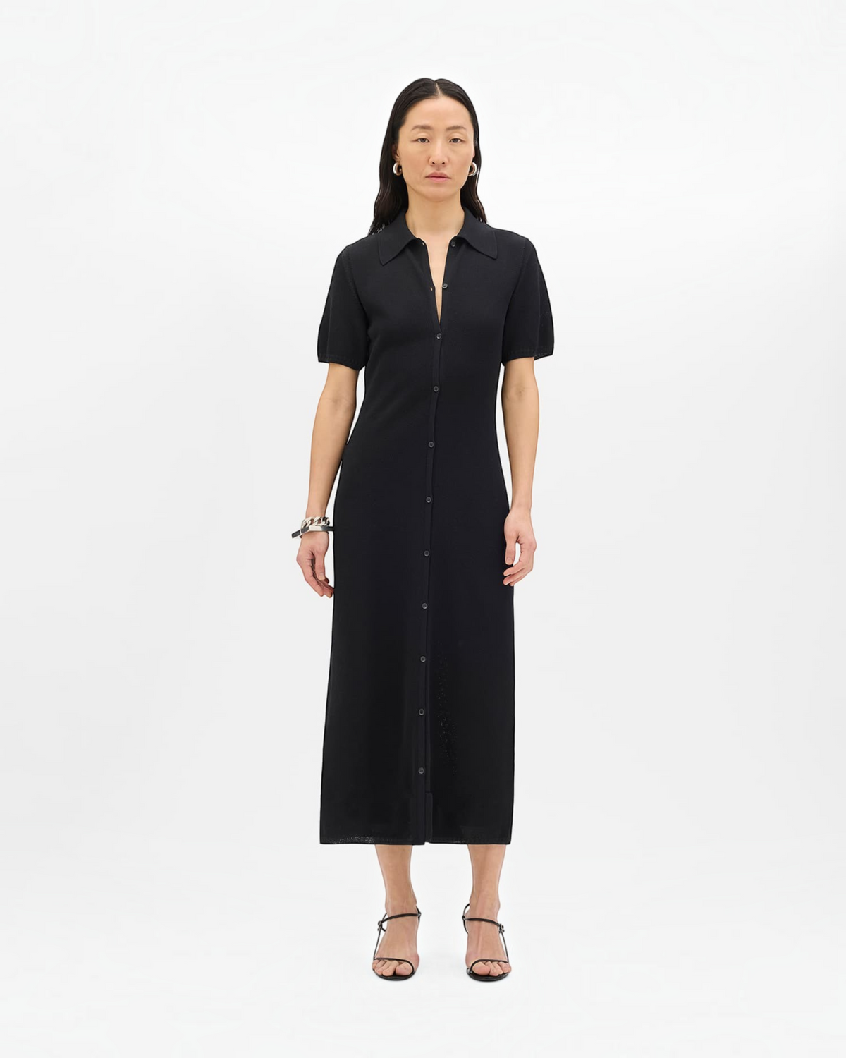 Model wearing a black Weldun midi-length pique polo dress with a button-front closure and short sleeves.