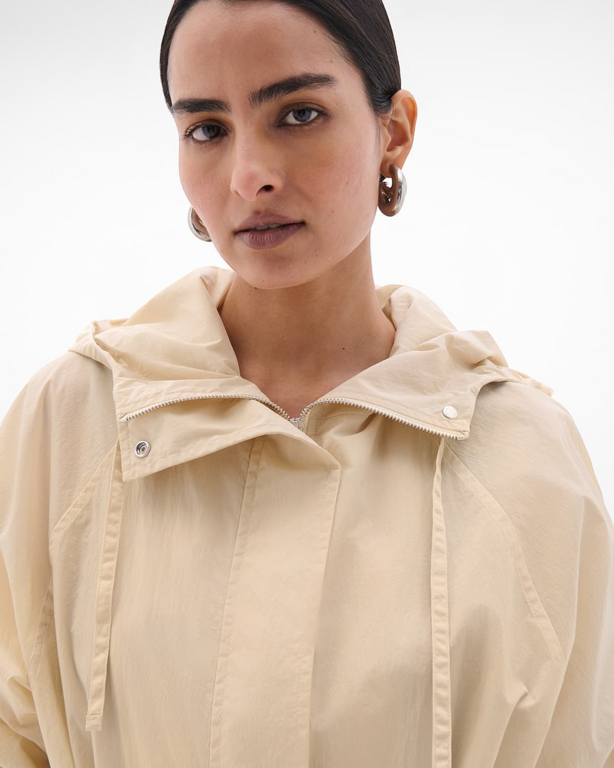 Weldun sand recycled nylon anorak with an oversized hood and zip-up front worn by a model