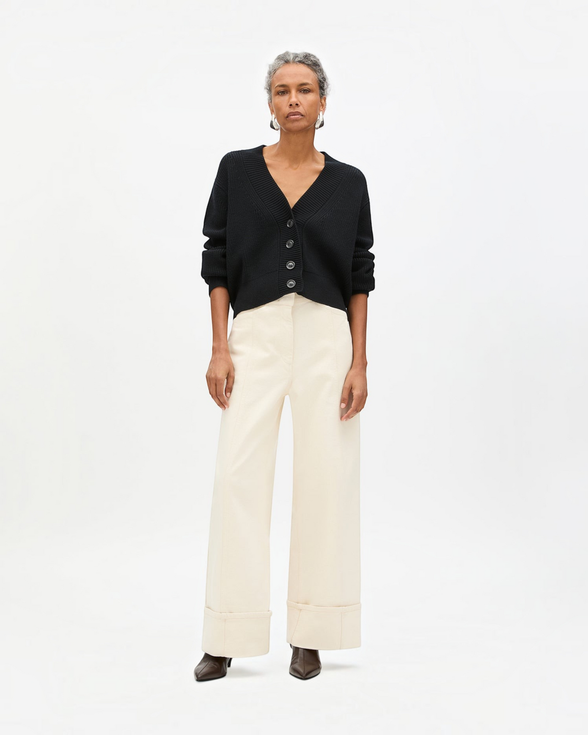Weldun black ribbed cropped cardigan with V-neck and oversized buttons worn by a model with cream wide-leg trousers