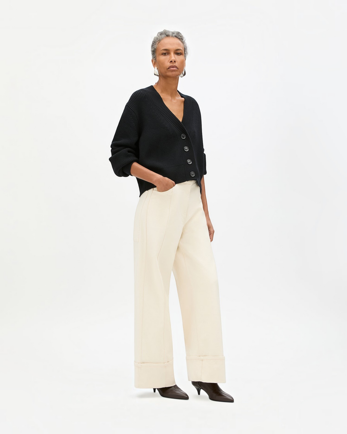 Weldun black ribbed cropped cardigan with V-neck and oversized buttons worn by a model with cream wide-leg trousers