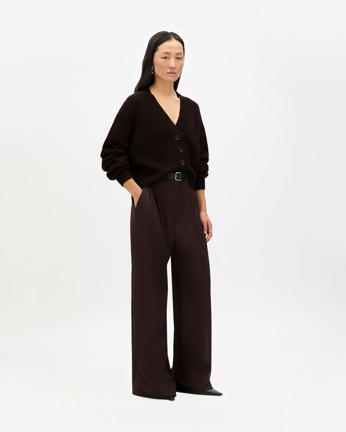 Model wearing a Weldun chocolate brown ribbed cropped cardigan with dropped shoulders and front button closure.