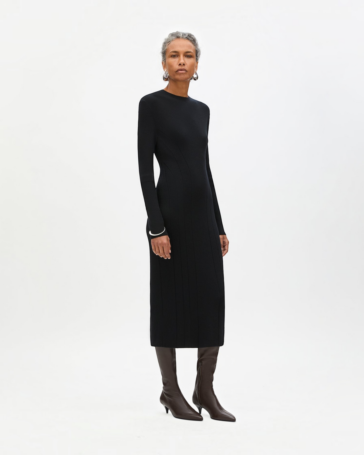 Weldun black tea length rib knit dress with long sleeves and curved seaming worn by a model with brown boots