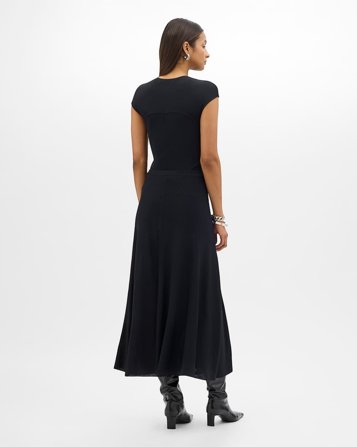 Weldun black seamed fitted top worn by a model with a matching skirt and black boots, back view