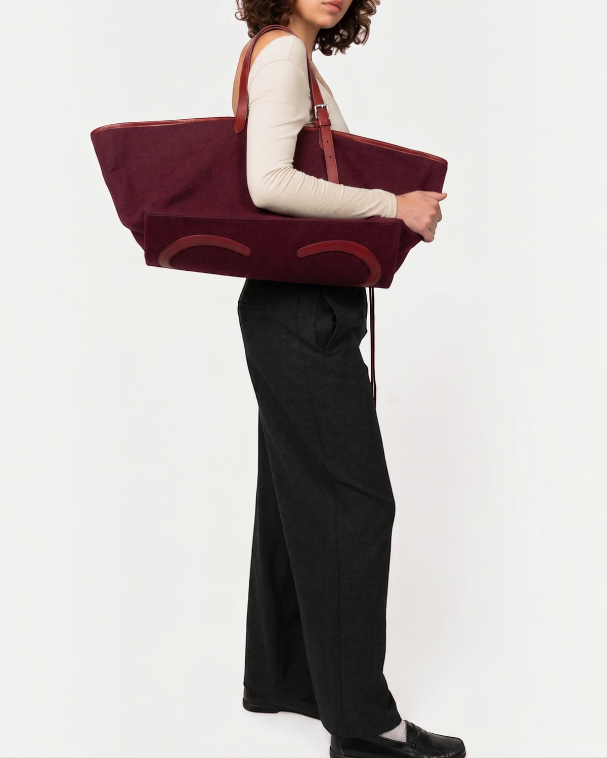 Weldun Leonora Weekend Canvas Carryall in deep burgundy with leather trim, worn over the shoulder by a model.