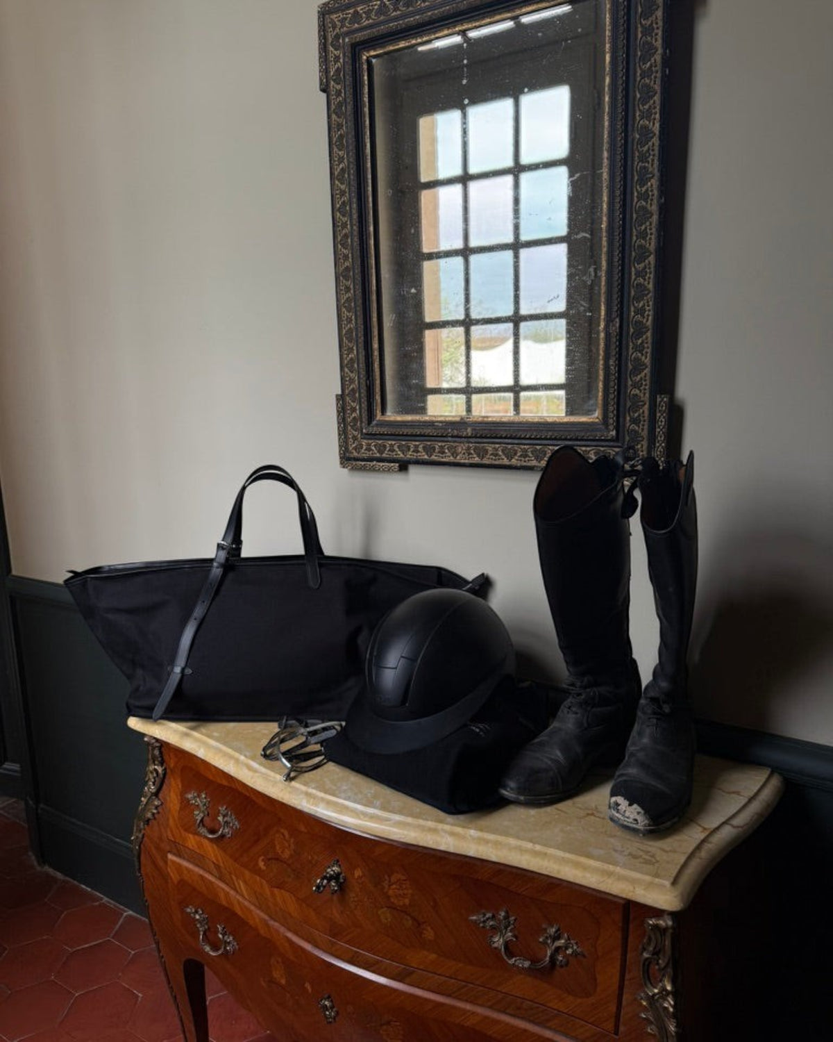 Weldun Leonora Weekend Canvas Carryall in black with leather trim, displayed on a dresser with riding gear.