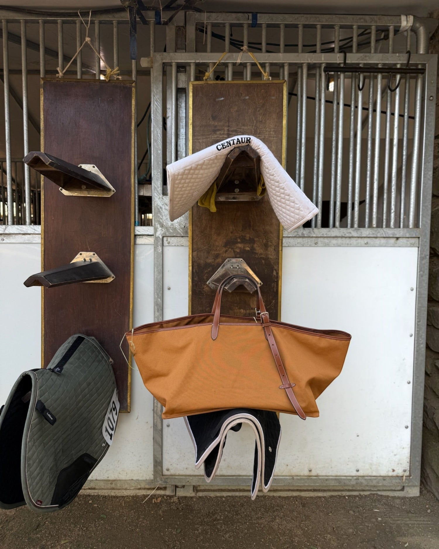 Weldun Leonora Weekend Canvas Carryall in tan with cowhide leather trim hanging in a stable setting