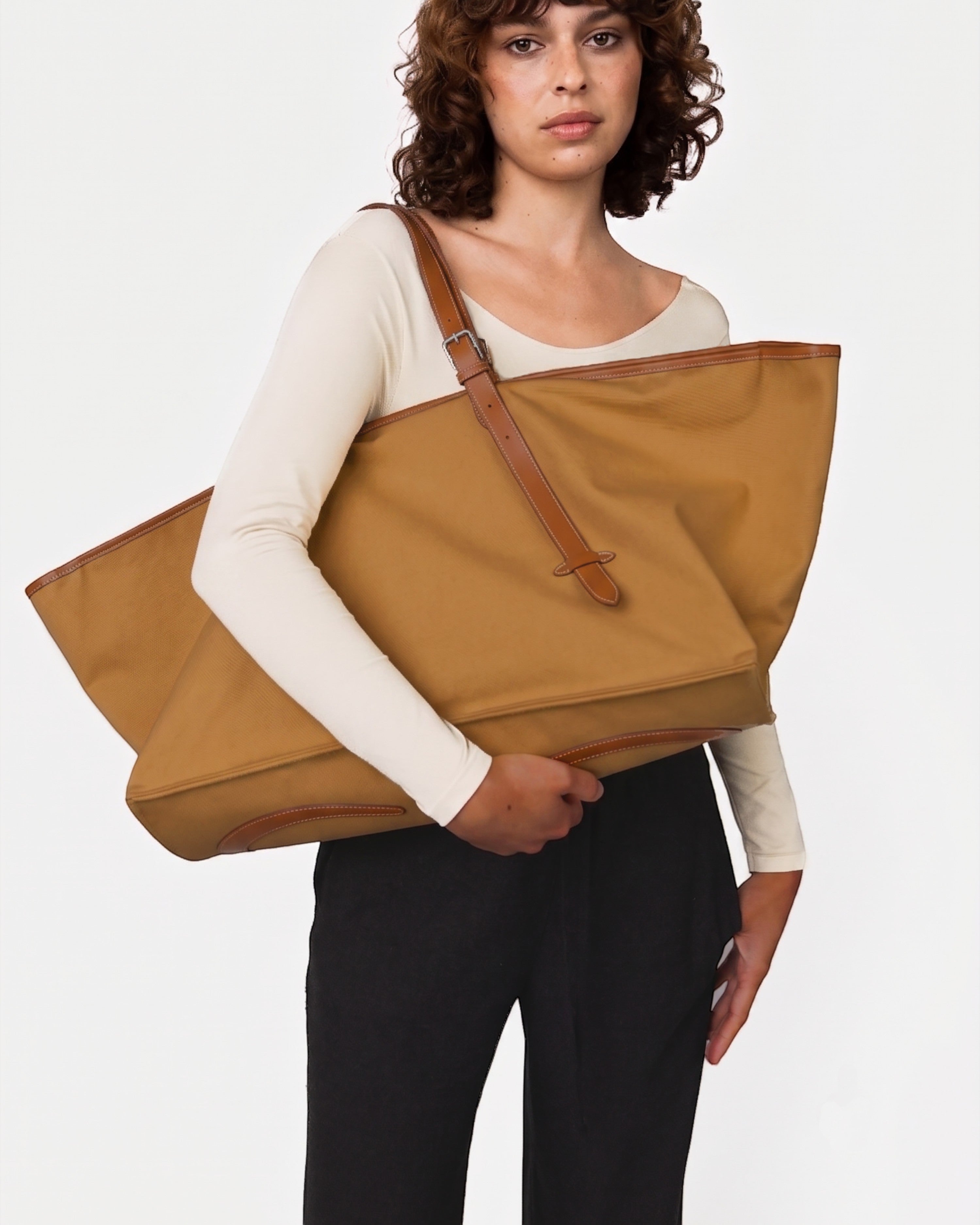 Weldun Leonora oversized tan canvas weekend carryall with brown leather trim held by a model