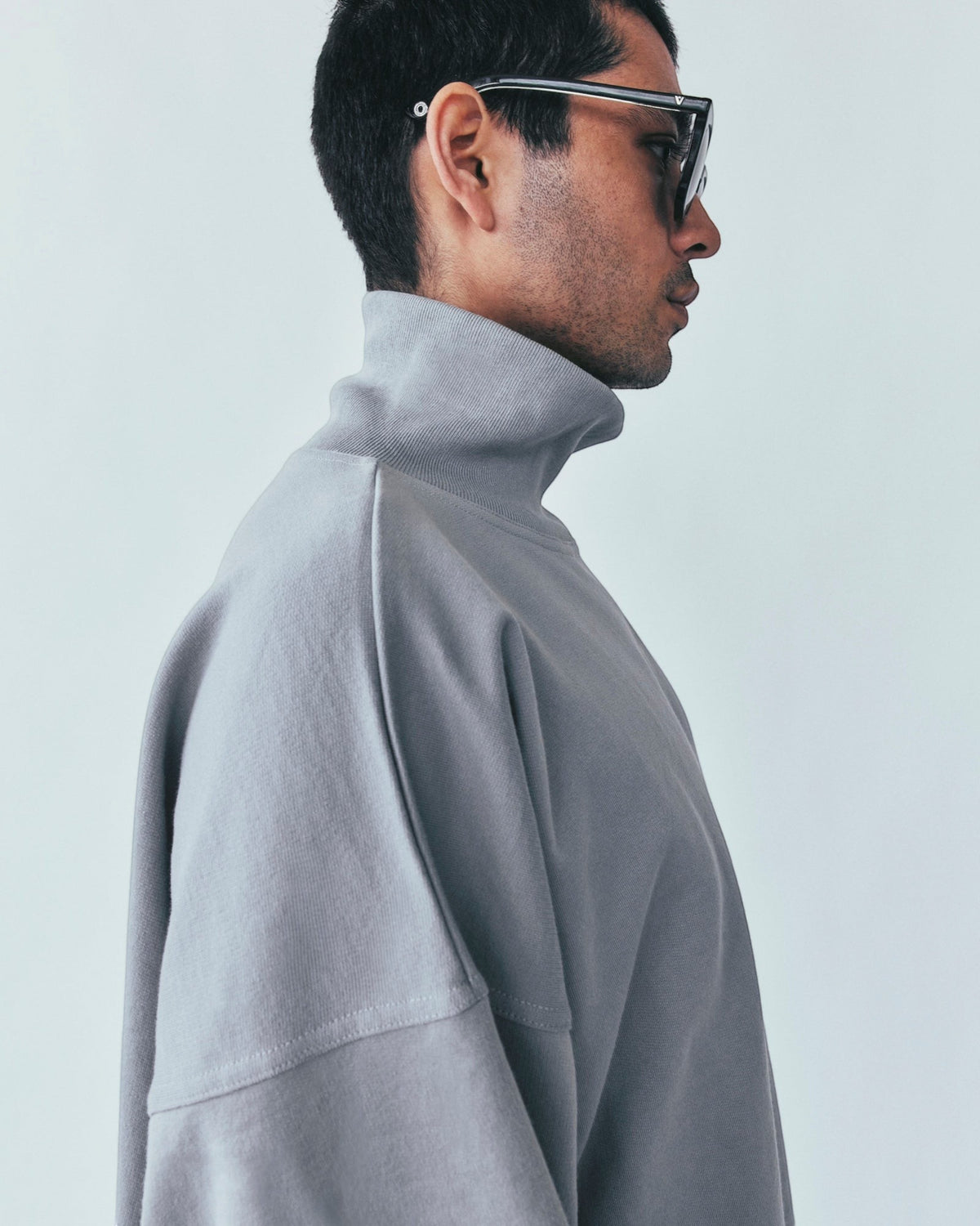 Weldun grey high neck sweatshirt in organic cotton with a relaxed boxy fit worn by a man in profile view