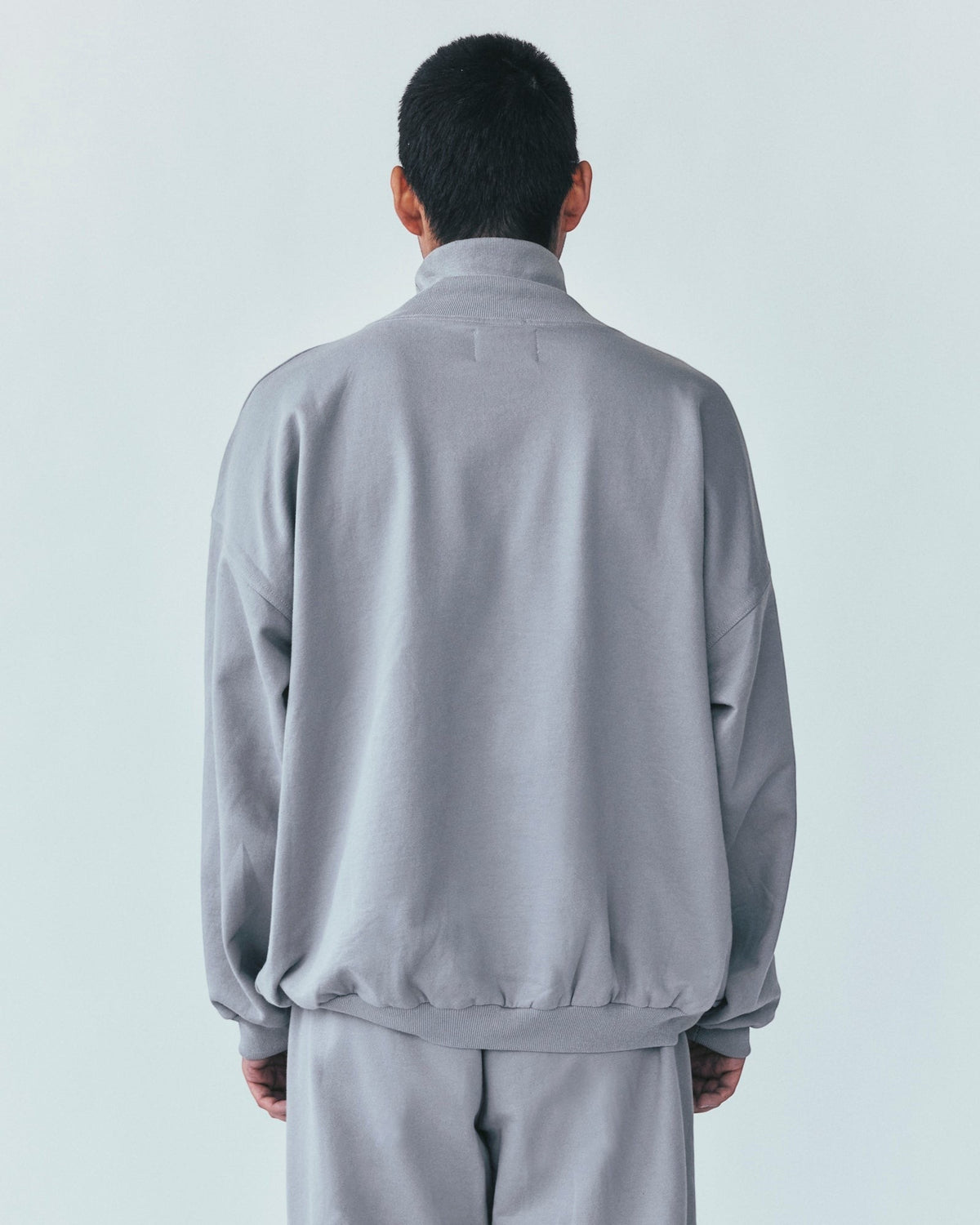 Back view of a person wearing a Weldun grey high neck sweatshirt in organic cotton with a relaxed boxy fit.