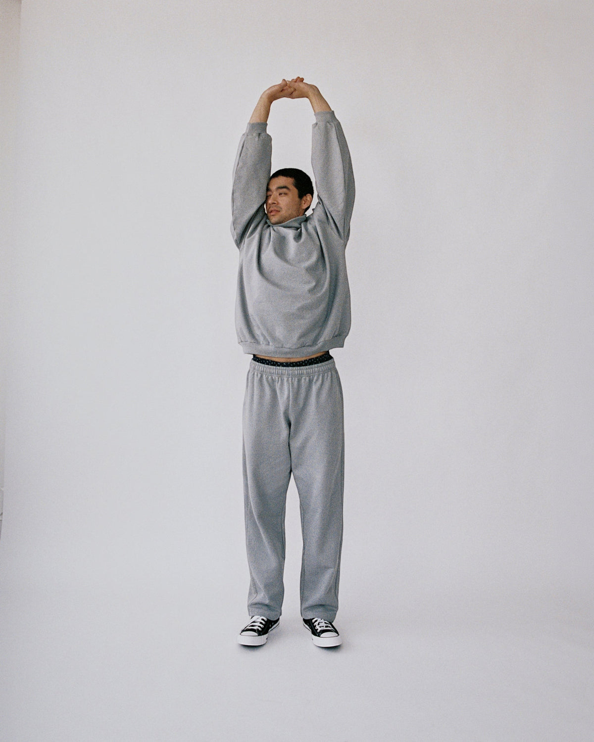 Weldun grey organic cotton sweatpants with a relaxed straight-leg fit worn by a man stretching in a studio
