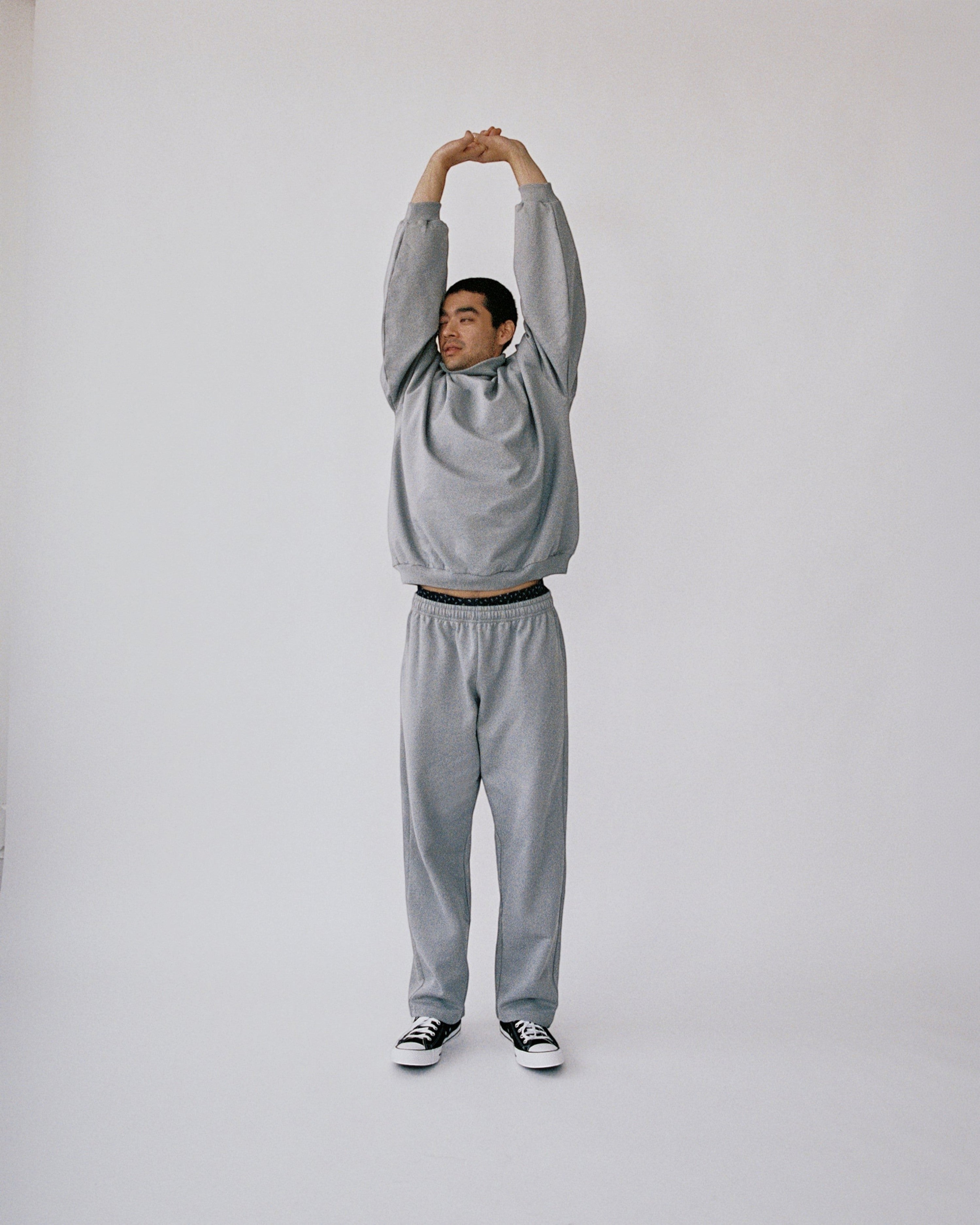 Weldun grey organic cotton sweatpants with a relaxed straight-leg fit worn by a man stretching in a studio