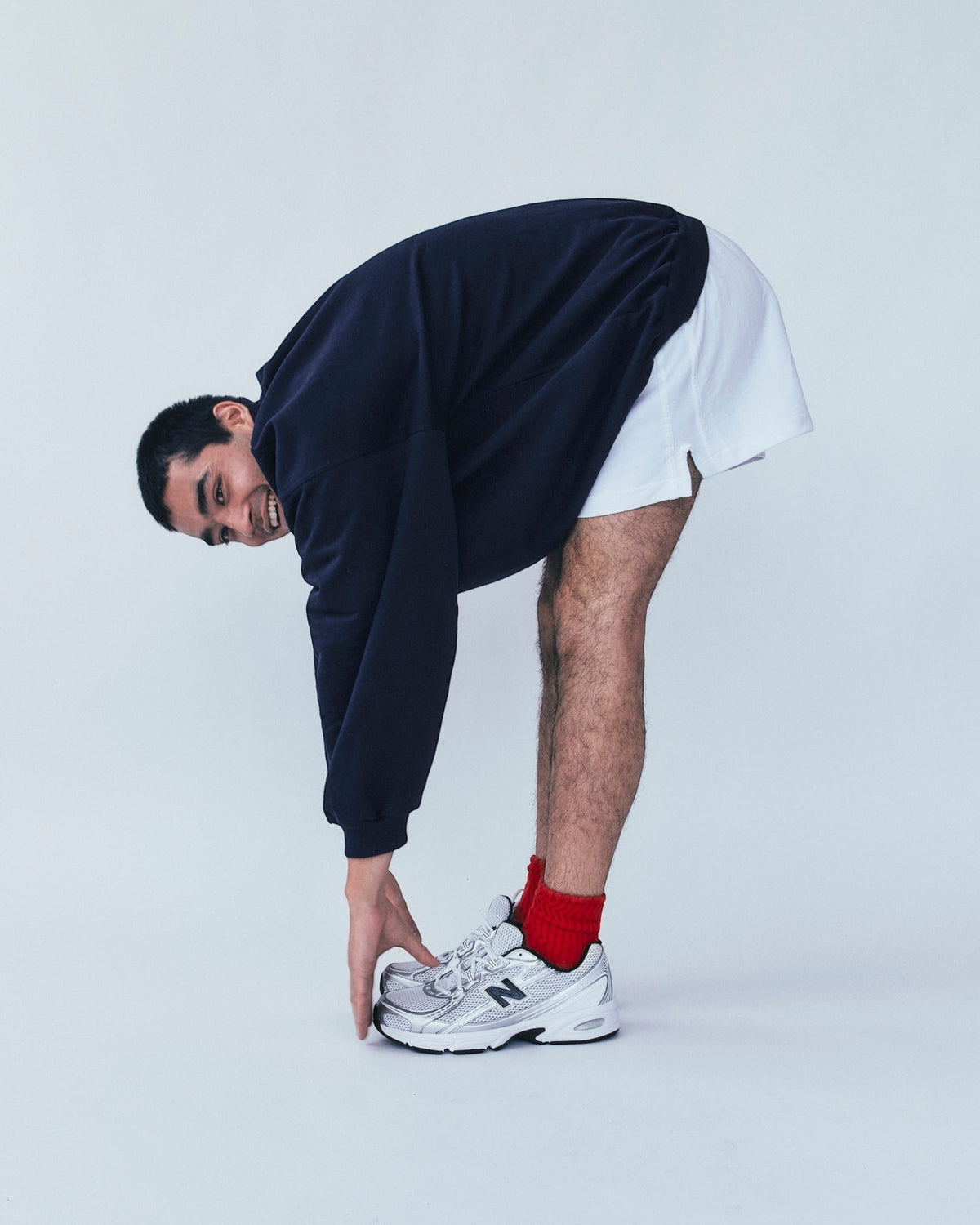 Weldun navy high neck sweatshirt in organic cotton with a boxy fit worn by a man bending over in white shorts