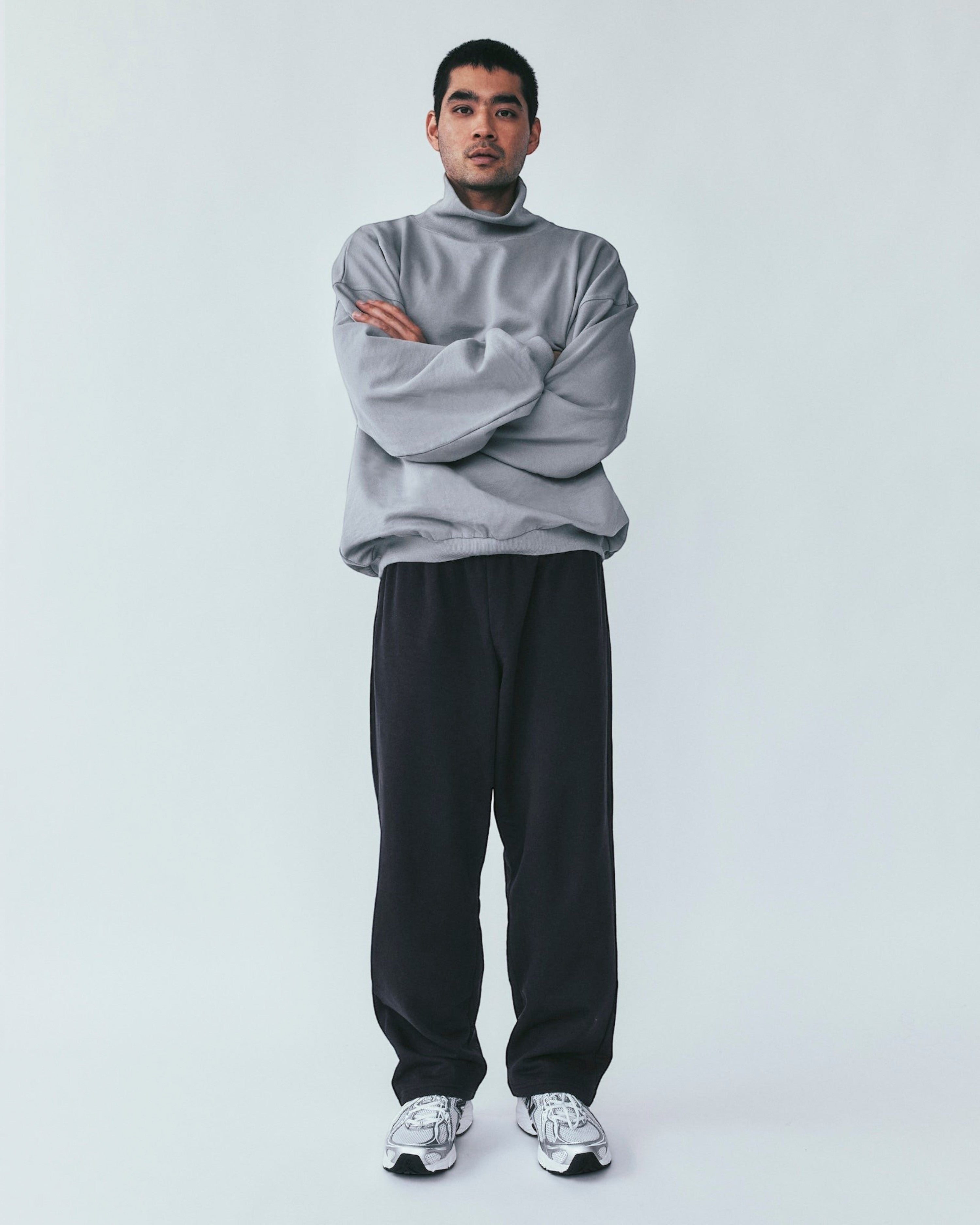 A model wearing Weldun navy organic cotton sweatpants with a relaxed straight-leg fit and a grey mock-neck sweatshirt.