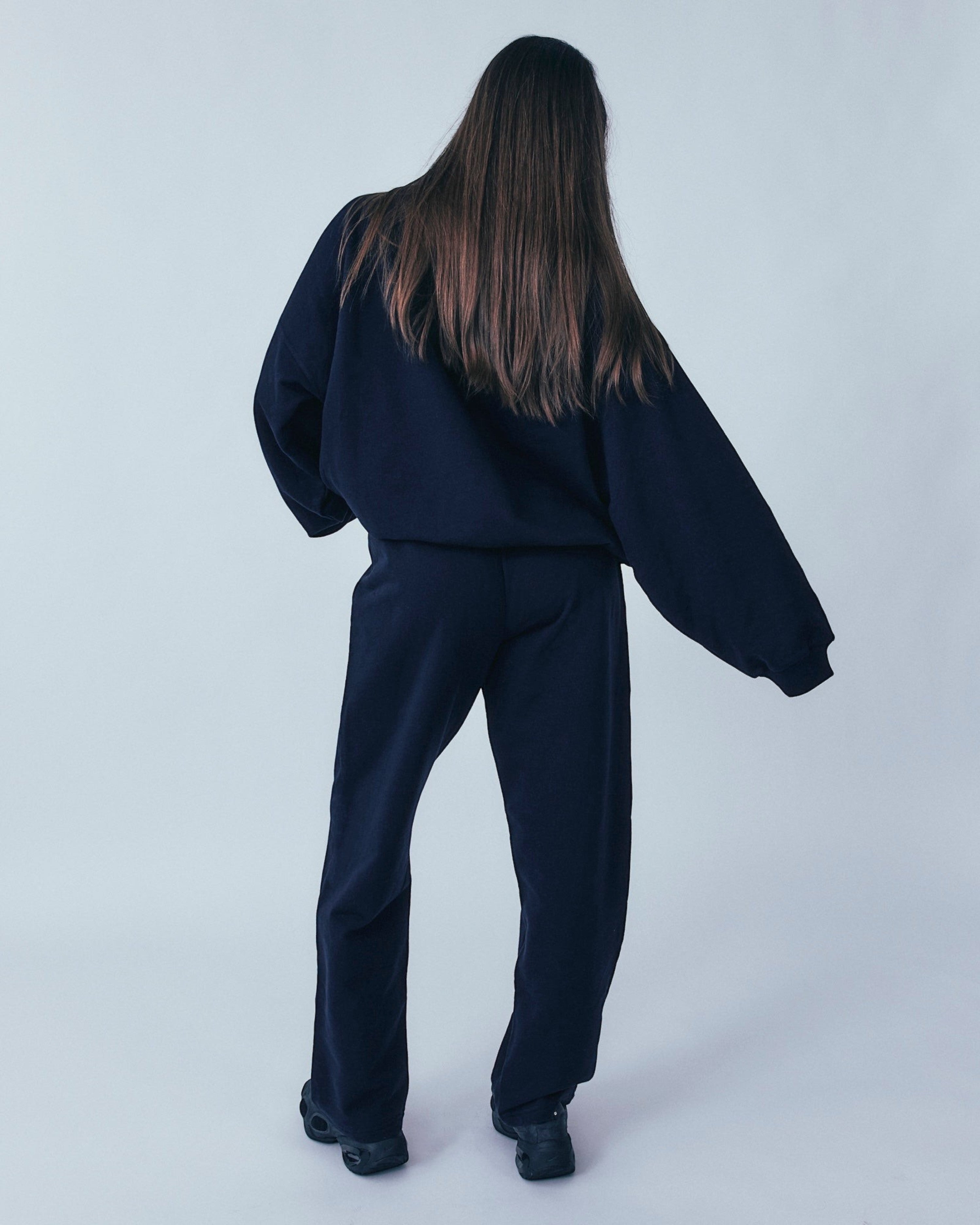 Weldun navy organic cotton sweatpants with a relaxed straight-leg fit, shown from the back on a model.