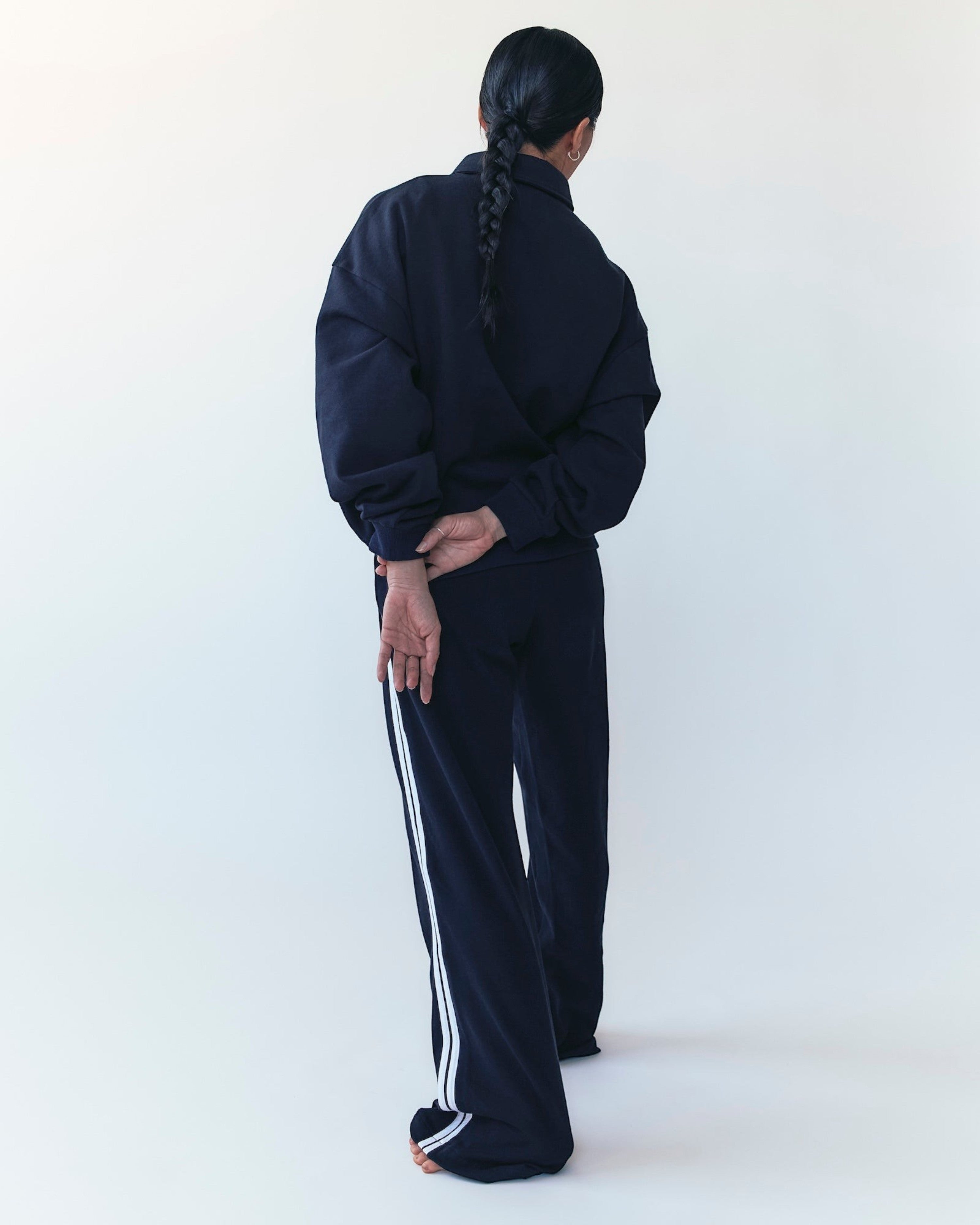 Weldun navy track pants with white side stripes in soft Japanese cotton terry, worn by a model from the back.