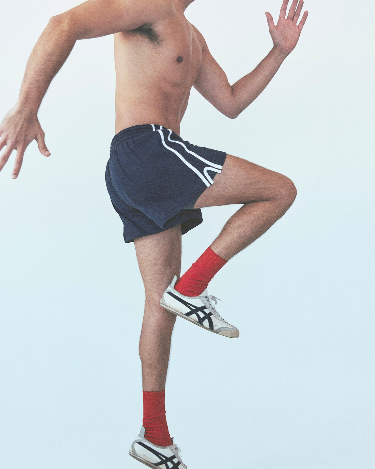 Weldun navy cotton terry basketball shorts with white side stripes worn by a man running in a studio setting