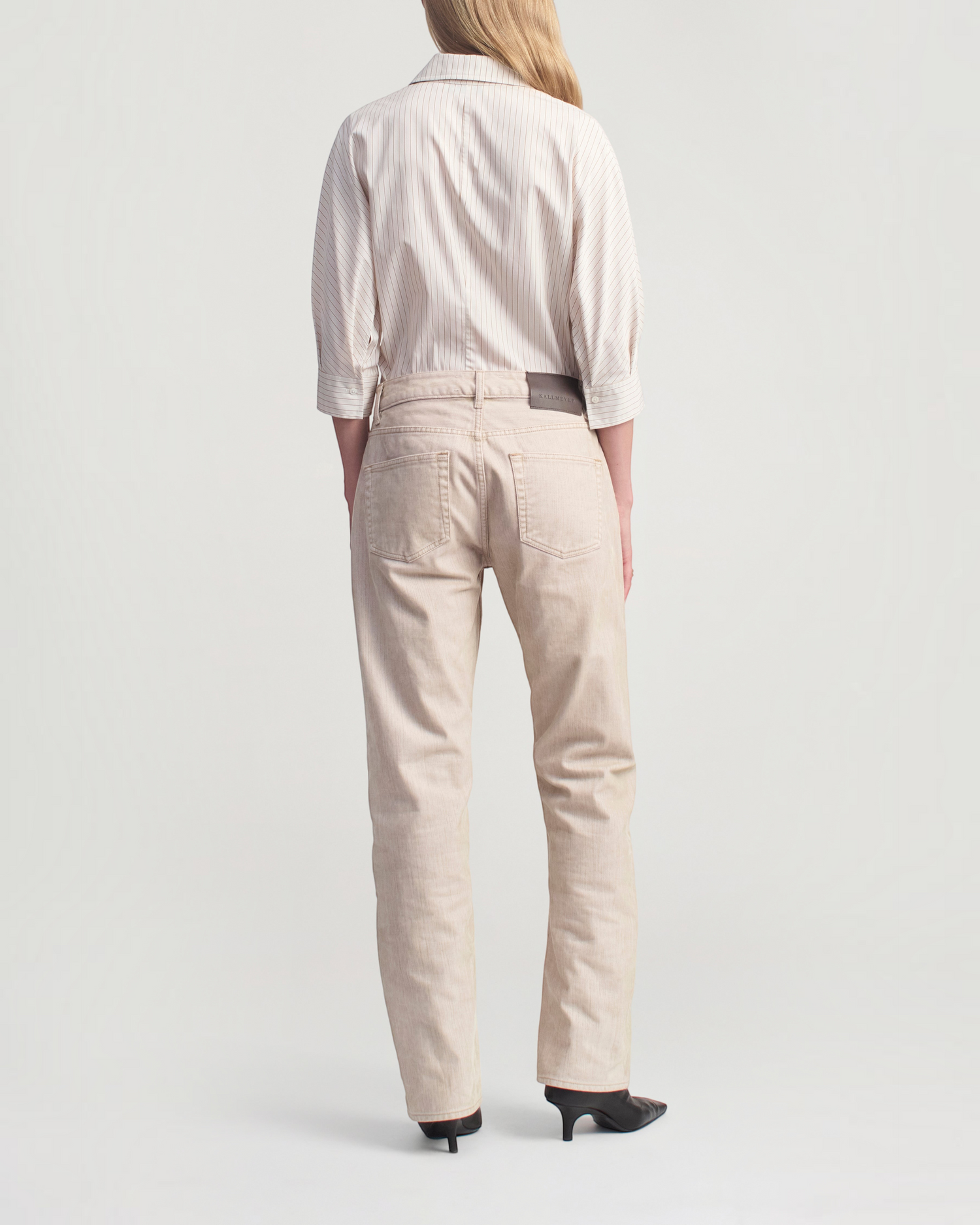 Weldun model wearing a sepia stripe cotton poplin button down shirt and light beige jeans from the back view.