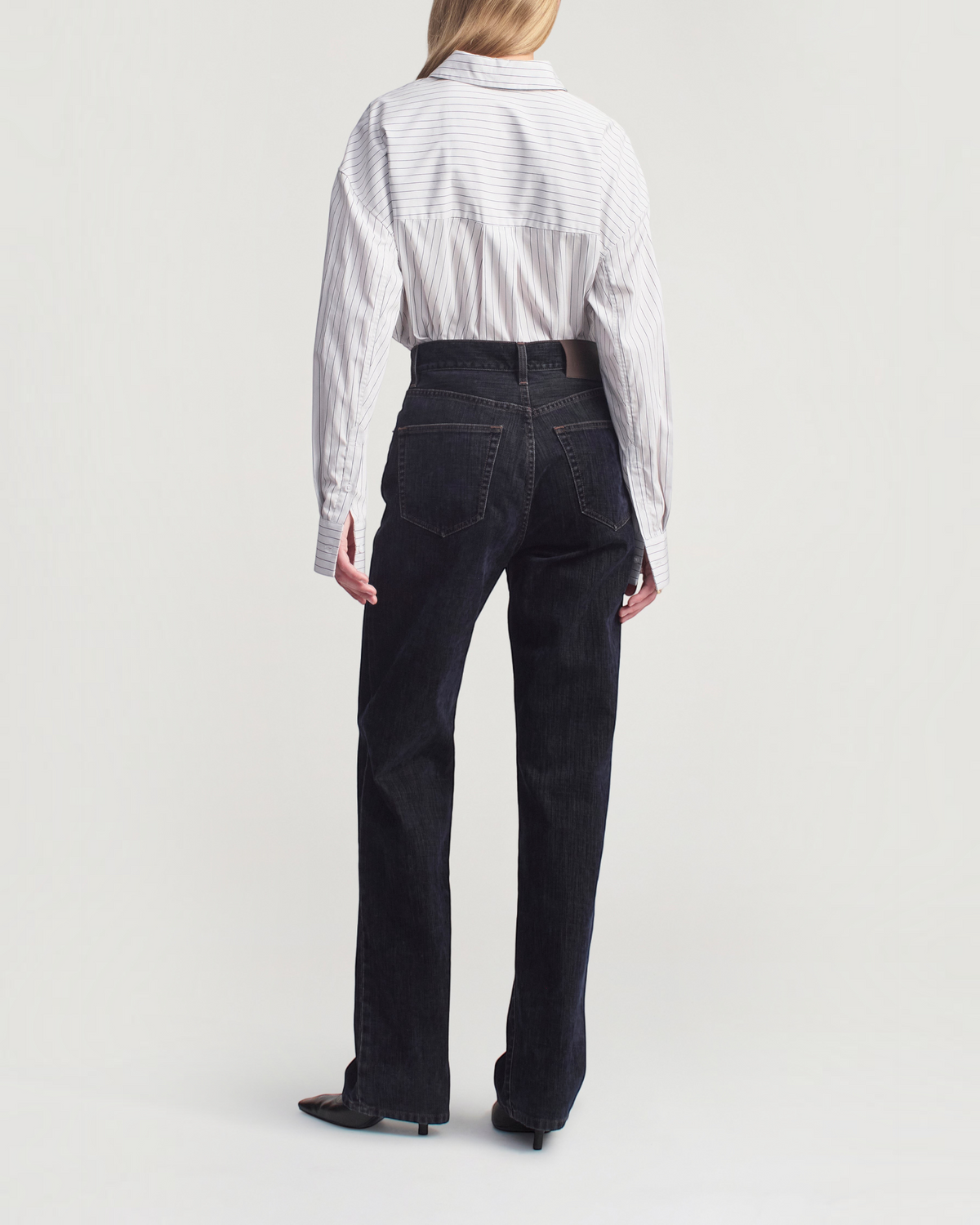 Weldun Dani button down shirt in navy stripe cotton poplin worn with dark denim jeans, back view
