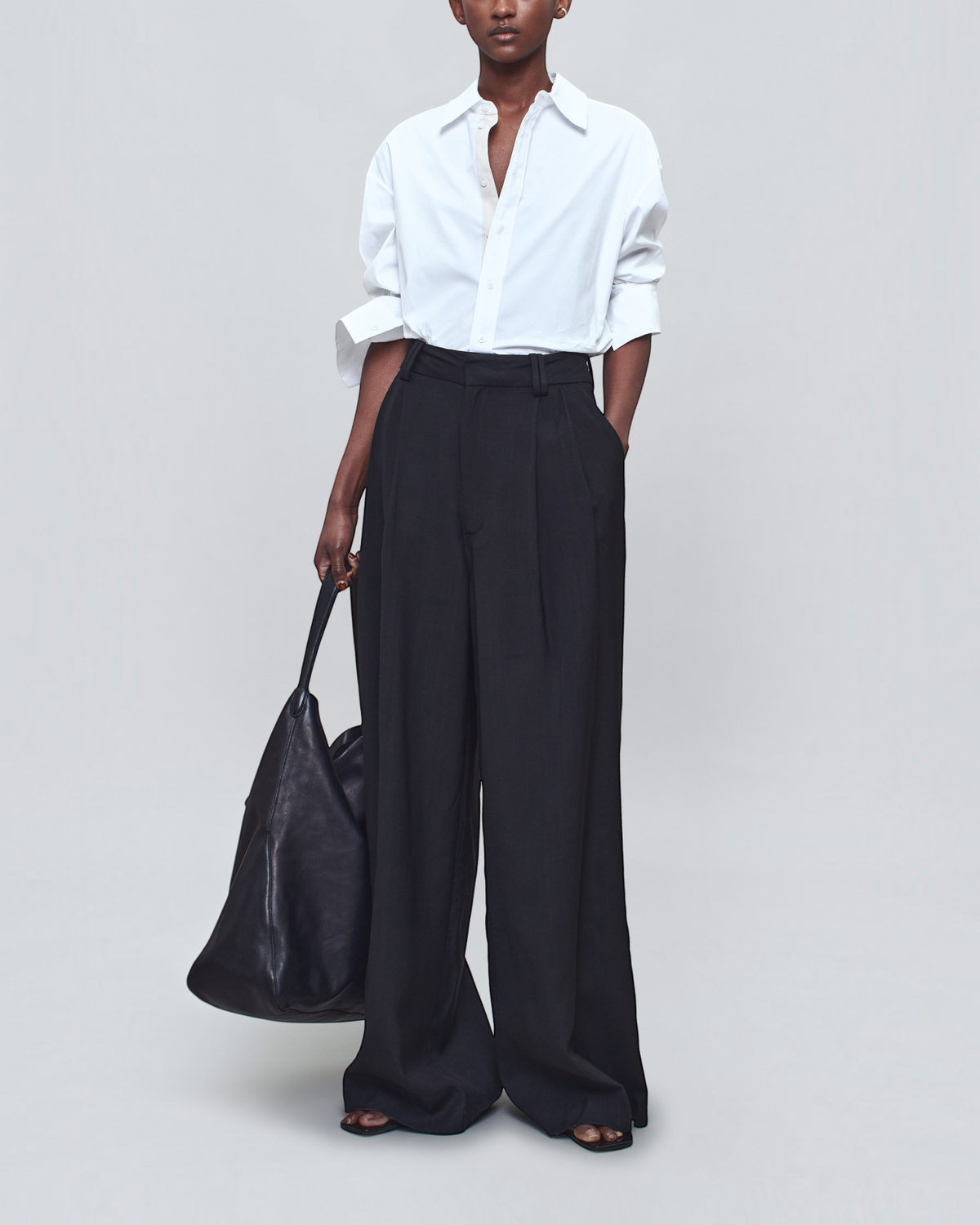 Weldun Dani white cotton poplin button down shirt worn with black wide-leg trousers and a large black leather tote bag