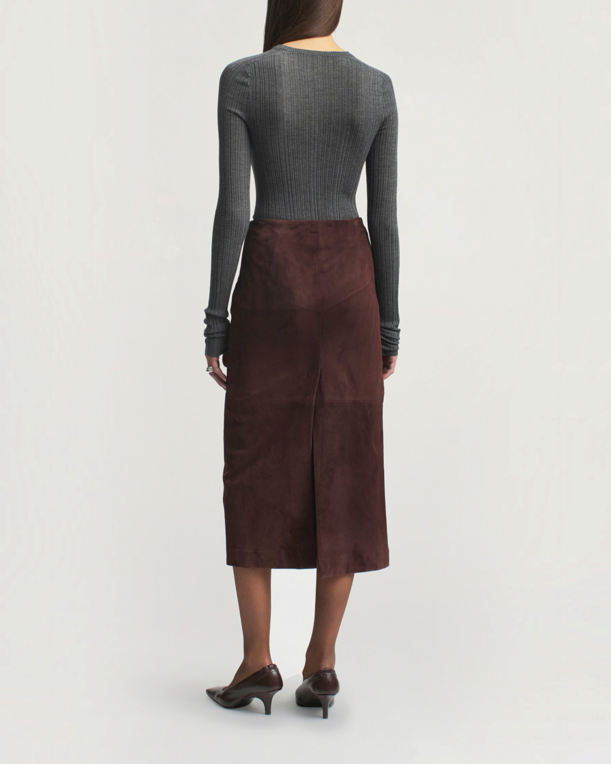Weldun model wearing a charcoal ribbed pointelle long sleeve top and a brown suede midi skirt from the back view.