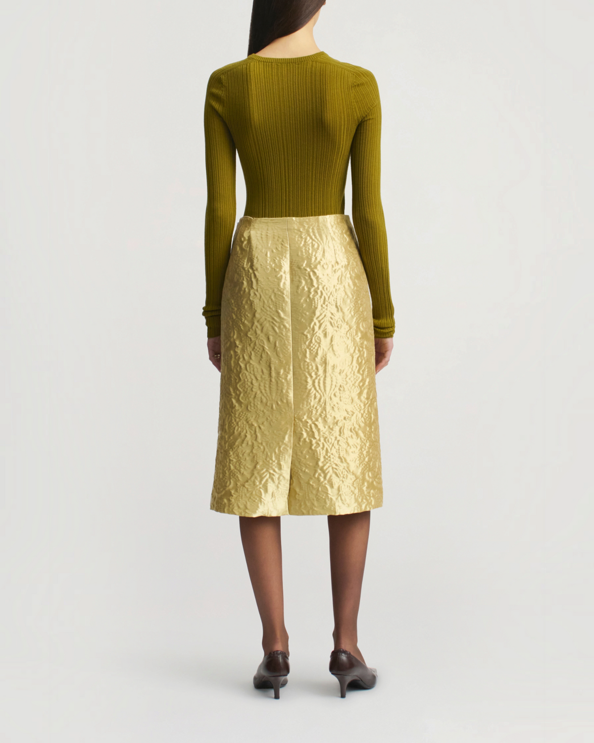 Weldun Fabi fitted olive green long sleeve pointelle top worn with a textured gold midi skirt, back view.