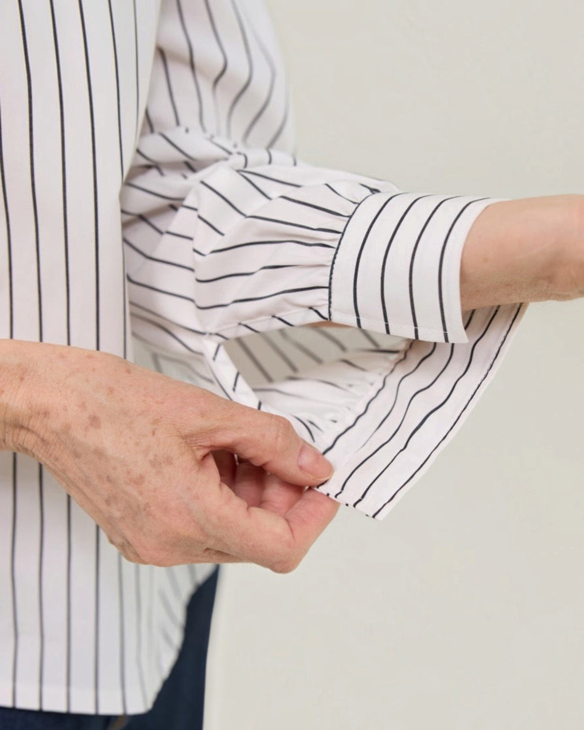 Weldun magnetic closure blouse in white with black stripes, showing detail of the easy-fasten magnetic cuff.