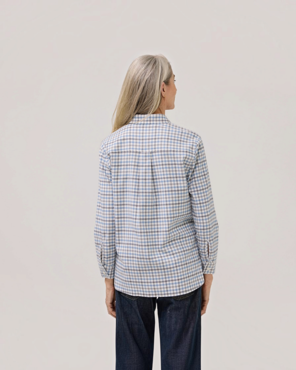 Back view of a woman wearing a Weldun blue and grey check adaptive flannel shirt with a relaxed A-line fit.