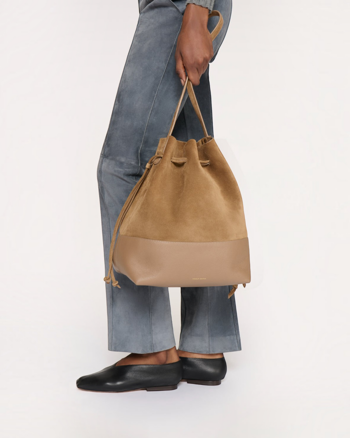 Weldun Mansur Gavriel Drawstring Cabas bucket bag in anise suede with top handles held by a model